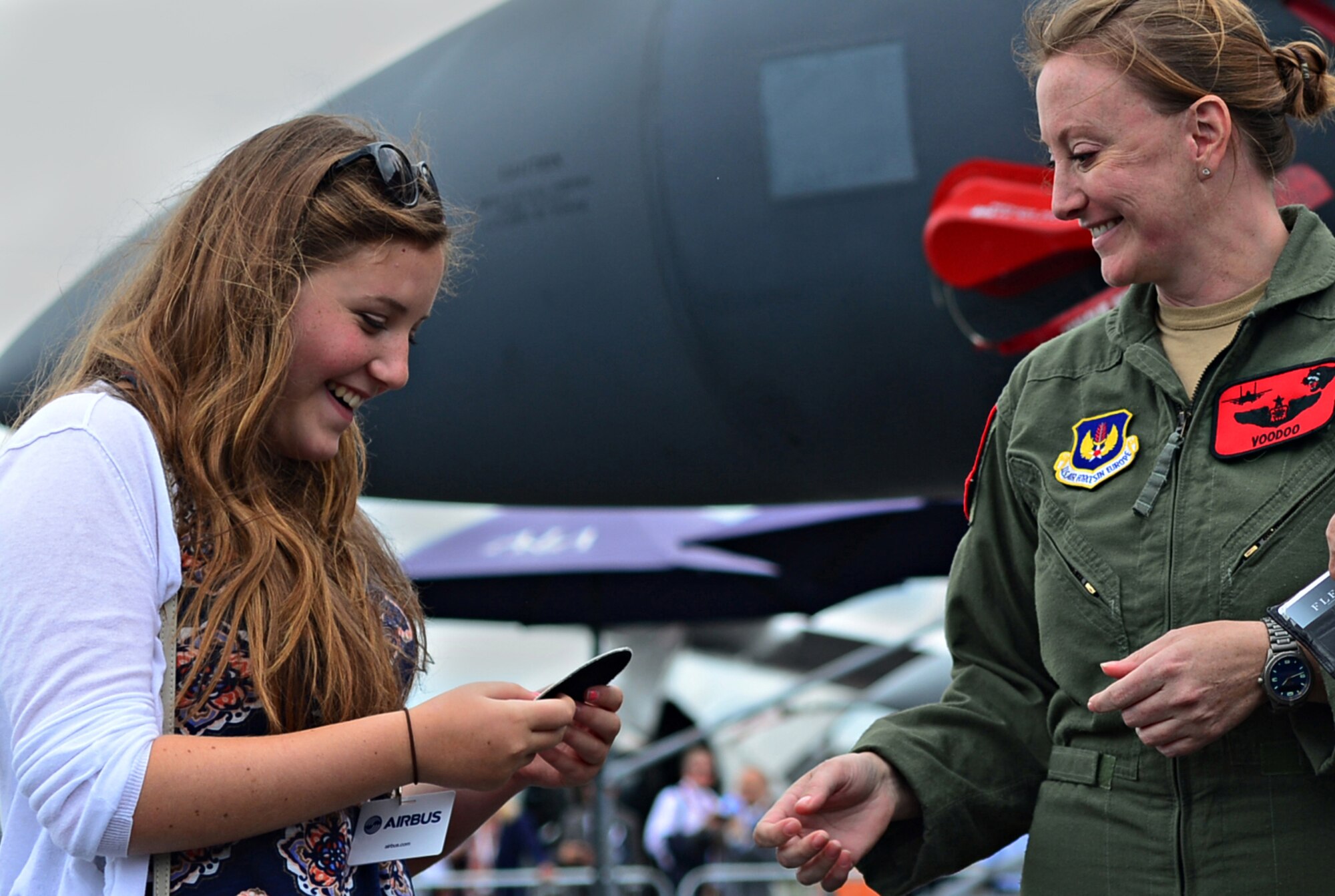 Maj. Claire Lundberg, 494th Fighter Squadron F-15E Strike Eagle weapons systems officer, gives a patch to a spectator during a public access showing at Farnborough International Airshow, England, July 18, 2014. FIA is held every two years, giving the opportunity for U.S. and its military allies to showcase leadership in aerospace technologies. (U.S. Air Force photo by Airman 1st Class Erin O'Shea/Released)