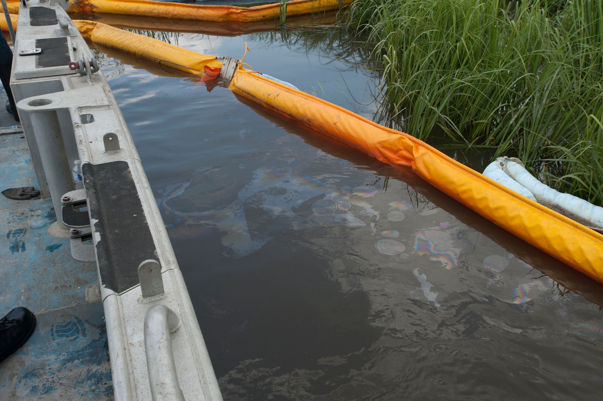JOINT BASE CHARLESTON, S.C. - Jet fuel gathers along a “boom” July 18, 2014, at a cleanup site where a drainage ditch enters the Ashley River. A multi-pronged team comprised of base civil engineers and members of the Environmental Protection Agency, the U.S. Coast Guard, Department of Health and Environmental Control and Moran Environmental Recovery are working to remove the fuel, which traveled from the Air Base during a leak July 16. Most of the fuel gathered, and is being collected, upstream along the drainage ditch. An inspection of the Ashley River boom July 19 revealed no further fuel collection or pooling. (U.S. Air Force photo/Staff Sgt. William O'Brien)
