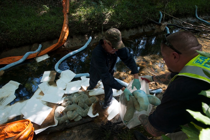 JOINT BASE CHARLESTON, S.C. - Cleanup crews remove jet fuel from one of three sites along a drainage ditch outside Joint Base Charleston - Air Base July 18, 2014, following a leak on the flightline two nights before. A multi-pronged team comprised of base civil engineers and members of the Environmental Protection Agency, the U.S. Coast Guard, Department of Health and Environmental Control and Moran Environmental Recovery have been working together to control and remove the spilled fuel. (U.S. Air Force photo/Staff Sgt. William O'Brien)