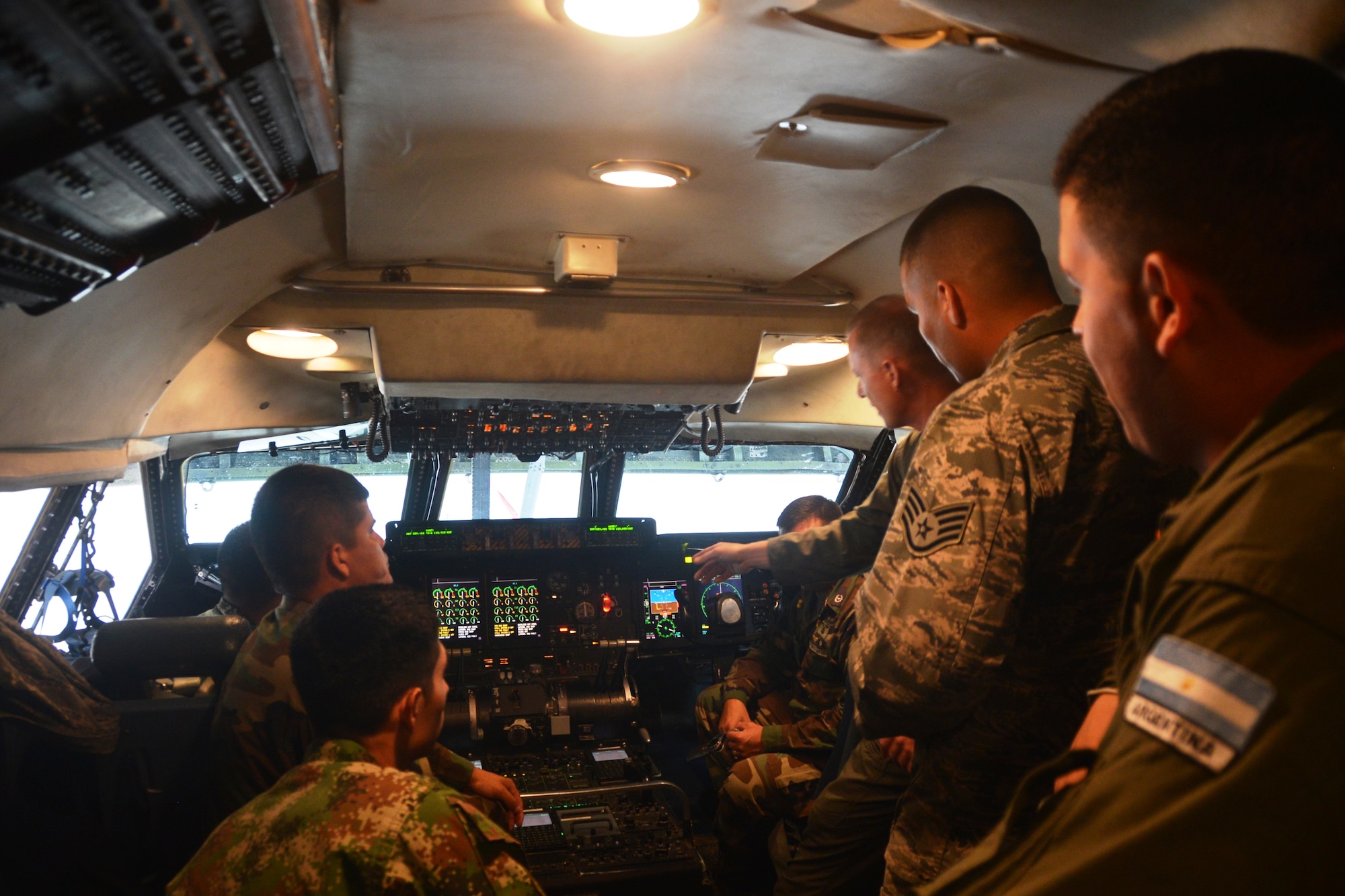 Major Doug Schoenenberger, (front right) a pilot from the 68th Airlift Squadron, Joint Base San Antonio-Lackland, Texas, introduces students from the Inter-American Air Forces Academy, JBSA-Lackland, Texas to the glass cockpit of the C-5A Galaxy during a tour of the 433rd Airlift Wing, July 17, 2014. The students received tour of a C-5A static, the wing's propulsion branch, the metals technology and structural repair shops, and how the “Alamo Wing” maintainer’s keep their C5As mission ready. (U.S. Air Force photo by Minnie Jones)