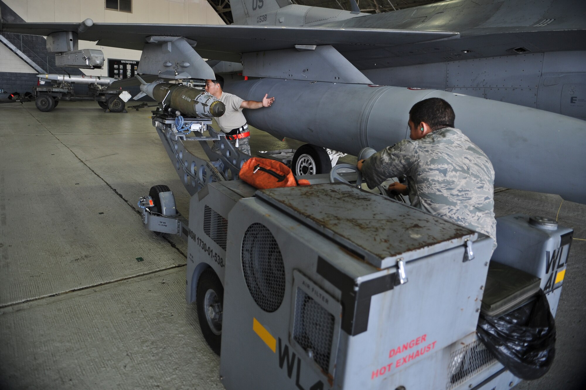 Staff Sgt. Sung Kim, 36th Aircraft Maintenance Unit weapons load crew chief, and Senior Airman Juan Urrutia, 36th AMU weapons load crew member, load a bomb onto an F-16 Fighting Falcon during a quarterly load crew competition on Osan Air Base, Republic of Korea, July 18, 2014. Load crews must prove themselves during monthly proficiency loads, quarterly evaluations and the everyday mission to participate in the competition. (U.S. Air Force photo/Senior Airman Matthew Lancaster)