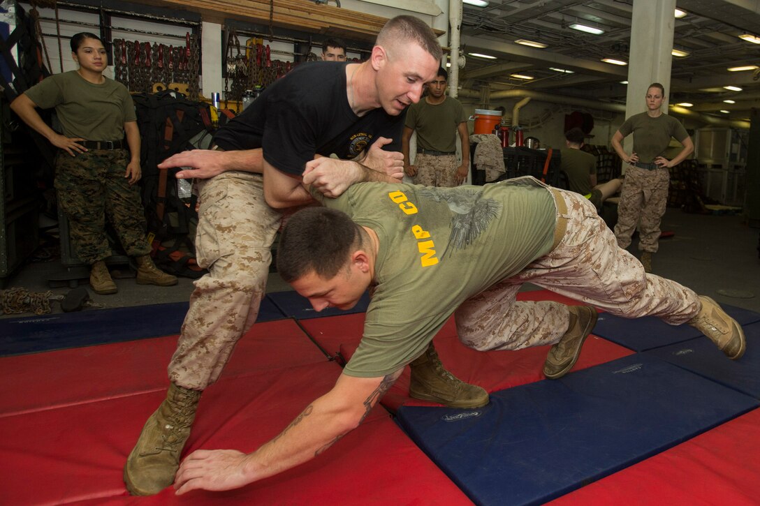 U.S. 5TH FLEET AREA OF RESPONSIBILITY (July 14, 2014) U.S. Marine Corps Staff Sgt. Kevin Morrow, left, 22nd Marine Expeditionary Unit (MEU) law enforcement detachment staff noncommissioned officer in charge and native of Waldwick, N.J., performs a mechanical advantage control hold technique on Sgt. Robert Votta, 22nd MEU law enforcement detachment noncommissioned officer in charge and native of Lakeview, Ore., as part of an oleoresin capsicum (OC) spray qualification course aboard the amphibious transport dock ship USS Mesa Verde (LPD 19). The 22nd MEU is deployed with the Bataan Amphibious Ready Group as a theater reserve and crisis response force throughout U.S. Central Command and the U.S. 5th Fleet area of responsibility. (U.S. Marine Corps photo by Cpl. Manuel A. Estrada/Released)