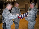 Members of the Alaska Air National Guard's 213th Space Warning Squadron perform an official flag folding ceremony at Clear Air Force Station to replace one burnt in a house explosion in Kansas Aug. 23, 2011. The home belonged to Annette Cook, a childhood friend of Alaska Air National Guard Tech. Sgt. Ricky Ramos, from Clear Air Force Station, who was spurred into action to help the Cook family after seeing pictures of the destruction online. The team also built a shadow box to display the new flag at Cook's new home.