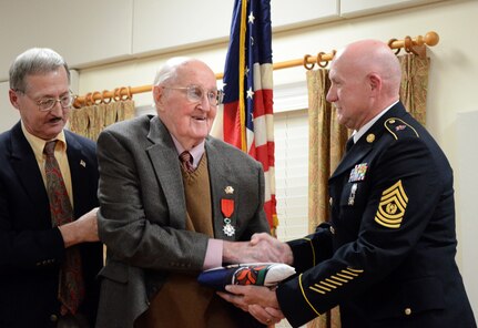 Army Command Sgt. Maj. Dennis Green, senior enlisted leader of the Virginia National Guard, presents a Virginia flag to Carl "Chubby" Proffitt Feb. 20, 2011. Proffitt was recently honored at the French Embassy in Washington, D.C., for his actions with the 29th Infantry Division during the D-Day invasion on June 6, 1944.