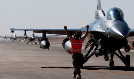 A crew chief directs the pilot of an F-16 Fighting Falcon to a parking spot after the jets arrived in Iraq Oct. 1, 2011. F-16 pilots, maintenance specialists and support personnel from the Ohio Air National Guard's 180th Fighter Wing deployed to Iraq in support of Operation New Dawn and provided close air support for more than 40,000 U.S. troops leaving the country near the end of last year.