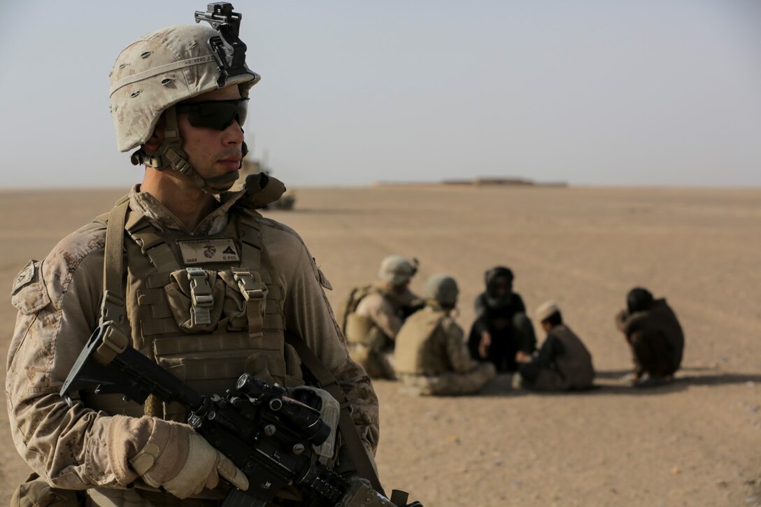 U.S. Marine Lance Cpl. Joseph Friedlander, a driver with Weapons Company, 1st Battalion, 2d Marine Regiment, provides security for Cpl. Justin Hinckley, a team leader, as he talks to a local family of the Washer district, during a security patrol in Helmand Province, Afghanistan on July 16, 2014. Patrols are conducted to disrupt enemy operations against Bastion- Leatherneck Complex. (Official U.S. Marine Corps photo by Cpl. John A. Martinez Jr. / Released)