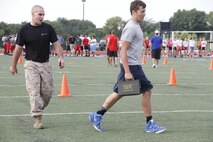 Sergeant Kyle F. Woodworth, a Recruiting Station Kansas City, Recruiting Sub-Station recruiter, encourages junior Aiden S. Byrd, a Park Hill High School Trojans free safety, during the maneuver-under-fire portion of the Marine Corps' Combat Fitness Test at the Trojans' football field July 17, 2014. Players from both the Trojan football and volleyball teams took part in the CFT. The CFT consists of an 880-meter sprint, 30-pound ammo-can lifts in two minutes, and the maneuver-under-fire. 