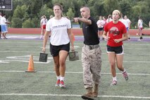 Sergeant Jeffrey P. Elliott, a Recruiting Station Kansas City, Recruiting Sub-Station Gladstone recruiter, points senior Katie D. Reichert, a Park Hill High School Trojans volleyball outside and inside hitter, to her next objective as she sprints during the maneuver-under-fire portion of the Marine Corps' Combat Fitness Test at the Trojans' football field July 20, 2014. Players from both the Trojan football and volleyball teams took part in the CFT. The CFT consists of an 880-meter sprint, 30-pound overhead ammo-can lifts in two minutes, and the maneuver-under-fire.  