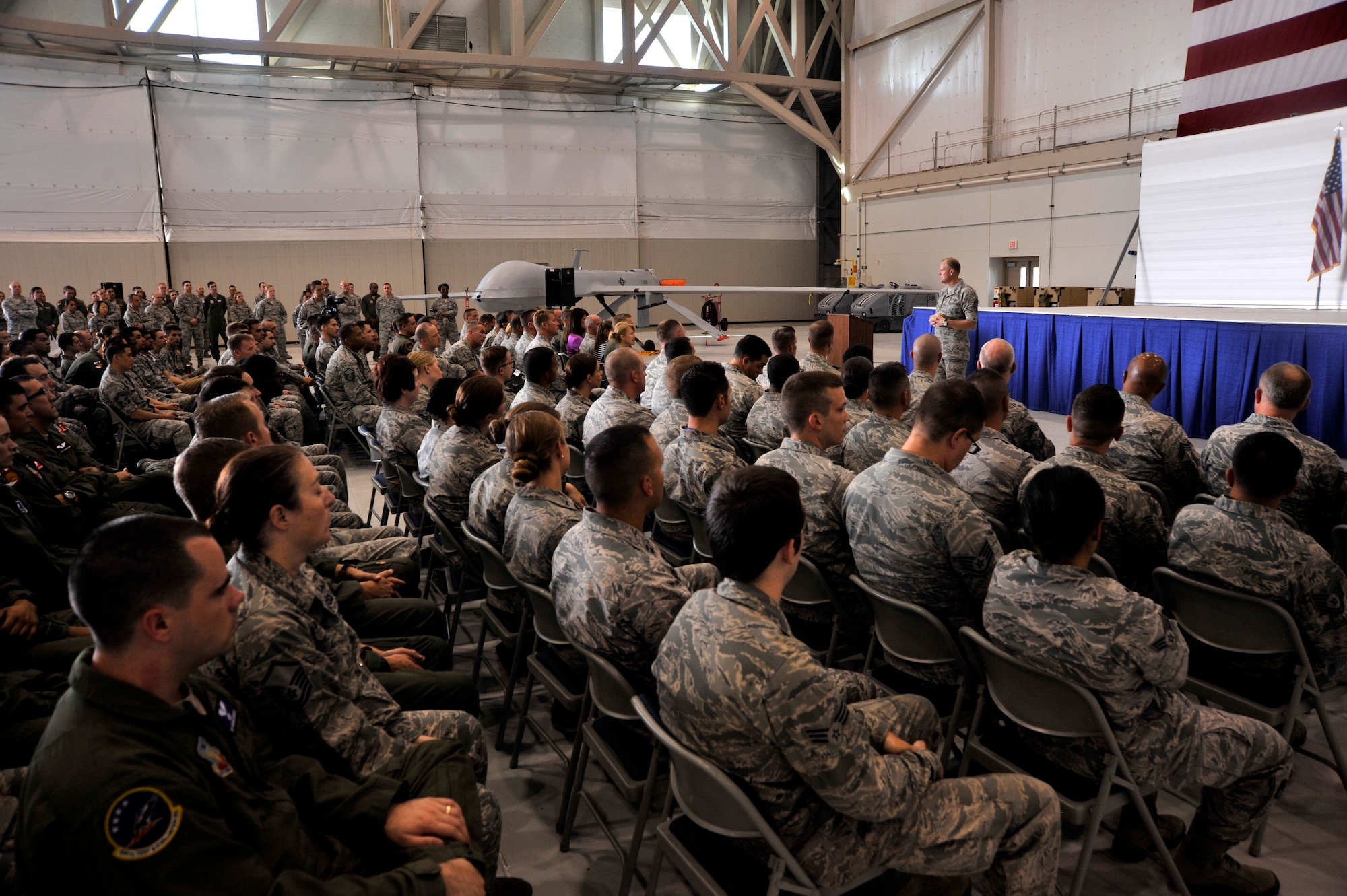 Airmen listen as Chief Master Sgt. of the Air Force James Cody delivers his enlisted perspective to the Airmen of the 432nd Wing/432nd Air Expeditionary Wing and 799th Air Base Group during an Airman’s Call at Creech Air Force Base, Nev., July 16, 2014. During his visit, Cody saw firsthand the operations tempo of the base’s Airmen.  Everyday Creech Airmen fulfill their mission by providing intelligence, reconnaissance and surveillance, maintenance, base support and defense, and other capabilities in support of combatant commanders around the globe.. (U.S. Air Force photo by Airman 1st Class Christian Clausen/RELEASED)
