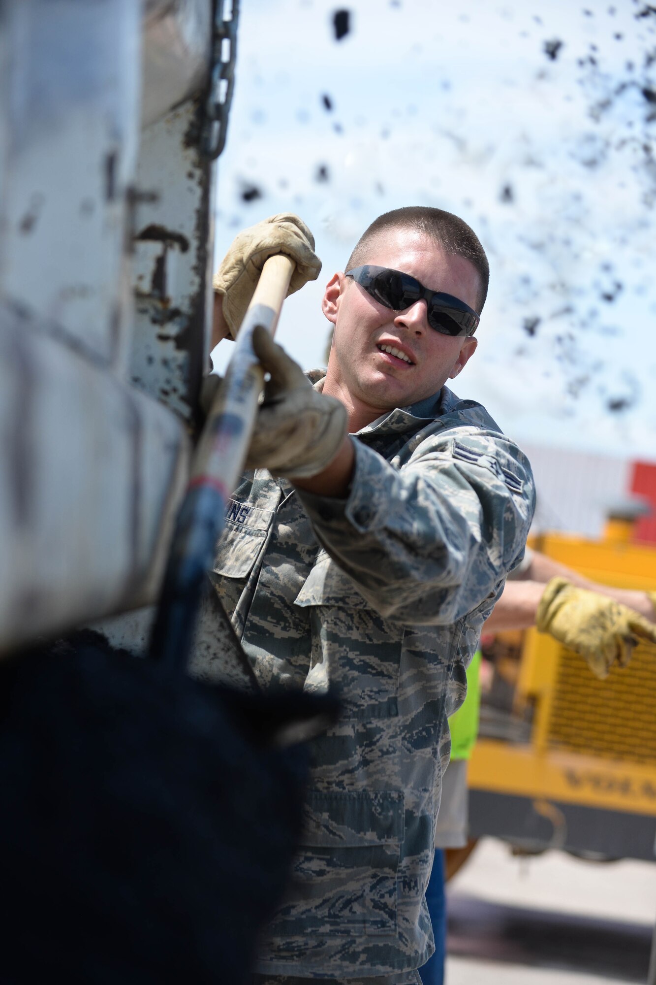 Airman 1st Class Tyler Hawkins, 28th Civil Engineer Squadron heavy equipment and pavement technician, spreads asphalt onto the flightline at Ellsworth Air Force Base, S.D., July 16, 2014 to repair runway damage. Heavy equipment specialists are responsible for paving and maintaining concrete and asphalt airstrips, operating heavy equipment, and sweeping for foreign object debris. (U.S. Air Force photo by Senior Airman Zachary Hada/Released)