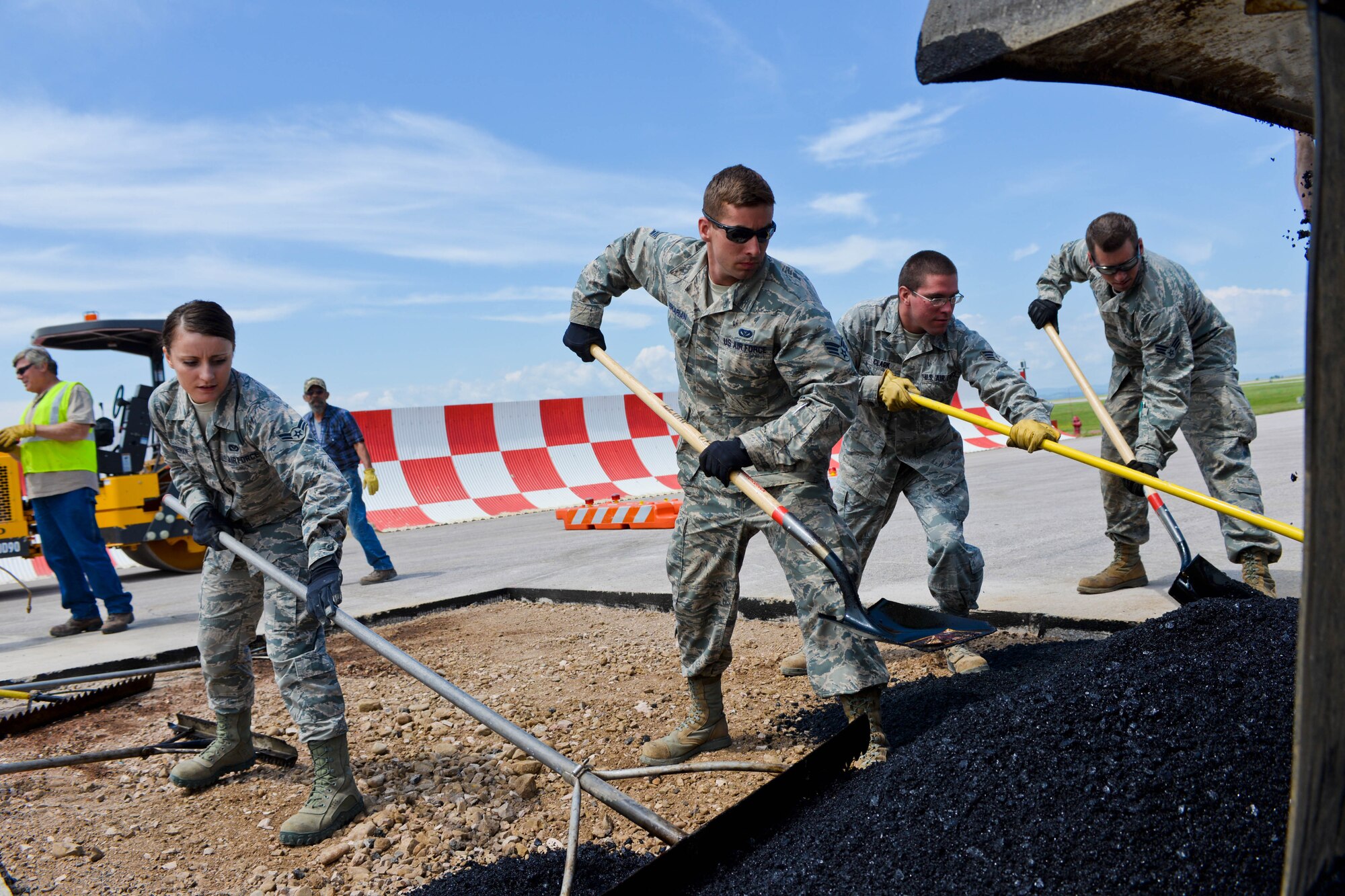 Heavy equipment and pavement Airmen assigned to the 28th Civil Engineer Squadron spread gravel and asphalt on the flightline at Ellsworth Air Force Base, S.D., July 16, 2014. Heavy equipment and pavement specialists are responsible for constructing and maintaining concrete and asphalt runways, aircraft parking aprons, and roads for Ellsworth. (U.S. Air Force photo by Senior Airman Zachary Hada/Released)
