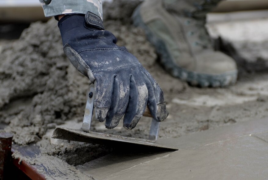 Airman 1st Class Kattie Schurman, 28th Civil Engineer Squadron heavy equipment and pavement technician, smoothes freshly-poured concrete to repair a sidewalk at Ellsworth Air Force Base, S.D., July 16, 2014. Heavy equipment and pavement technicians plan, construct and repair airfield pavements, roads, streets, curbs, surface mat, and other improved areas using paving and surfacing procedures. (U.S. Air Force photo by Senior Airman Zachary Hada/Released)