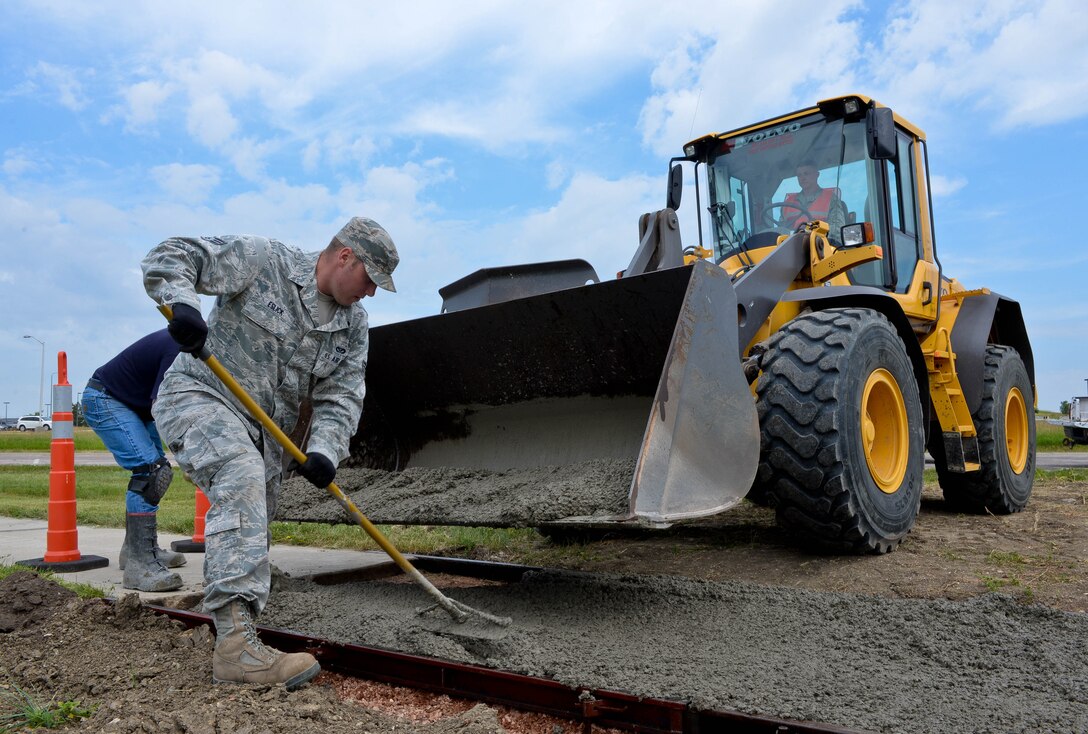 Senior Airman Nicholas Eslick, 28th Civil Engineer Squadron heavy equipment and pavement technician, spreads freshly-poured concrete for a new section of sidewalk at Ellsworth Air Force Base, S.D., July 16, 2014. Pavement and construction specialists operate and maintain heavy construction equipment such as front-end loaders, bulldozers, dump trucks, skid steer loaders and road graders to keep operations running at Ellsworth. (U.S. Air Force photo by Senior Airman Zachary Hada/Released)