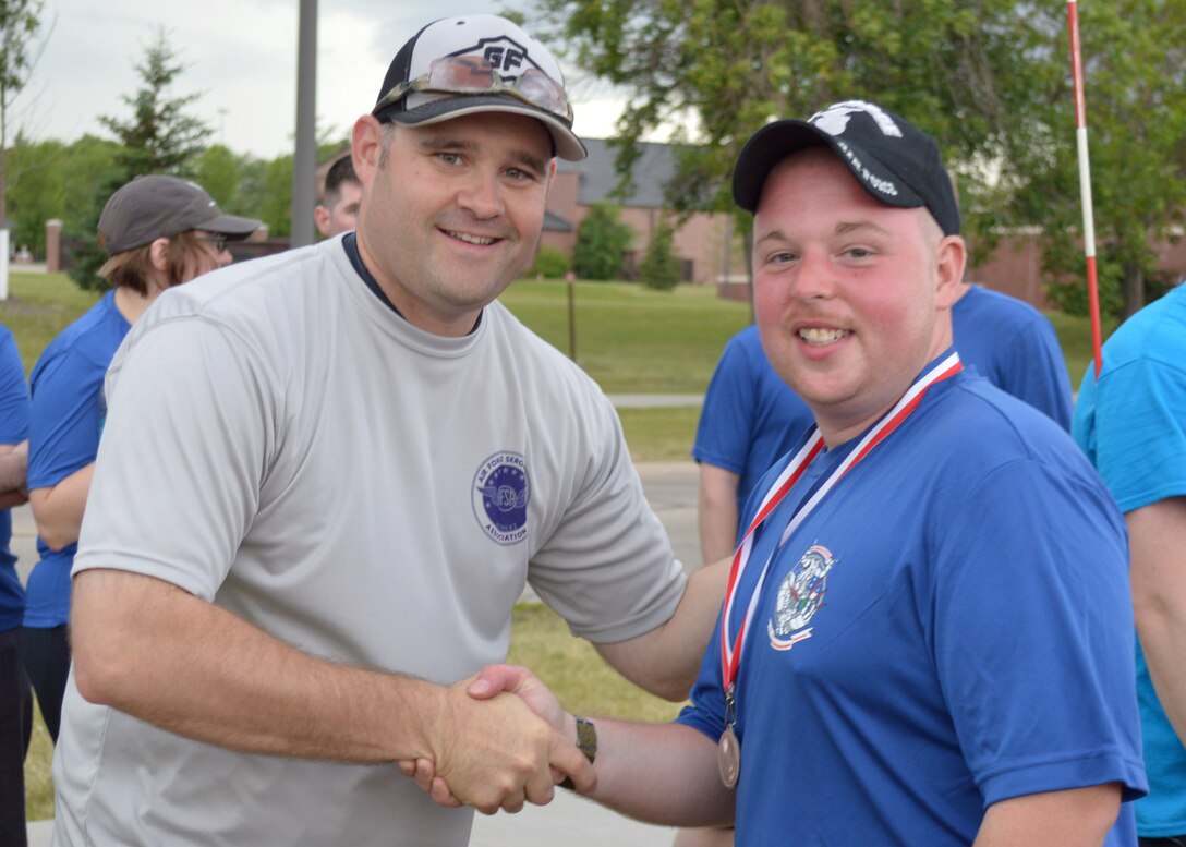 (Left) Tech. Sgt. Jared Langenstein, Air Force Sergeants Association Chapter 964 president, congratulates Staff Sgt. David Couch, 319th Communications Squadron unit deployment manager, for winning first place in the individual category during the 12-hour relay on July 18, 2014, on Grand Forks Air Force Base, N.D. Couch completed 100 laps around the base outdoor running track during the relay which helped raise money for the Wounded Warrior Project and the local Air Force Sergeants Association. (U.S. Air Force photo/Senior Airman Xavier Navarro)