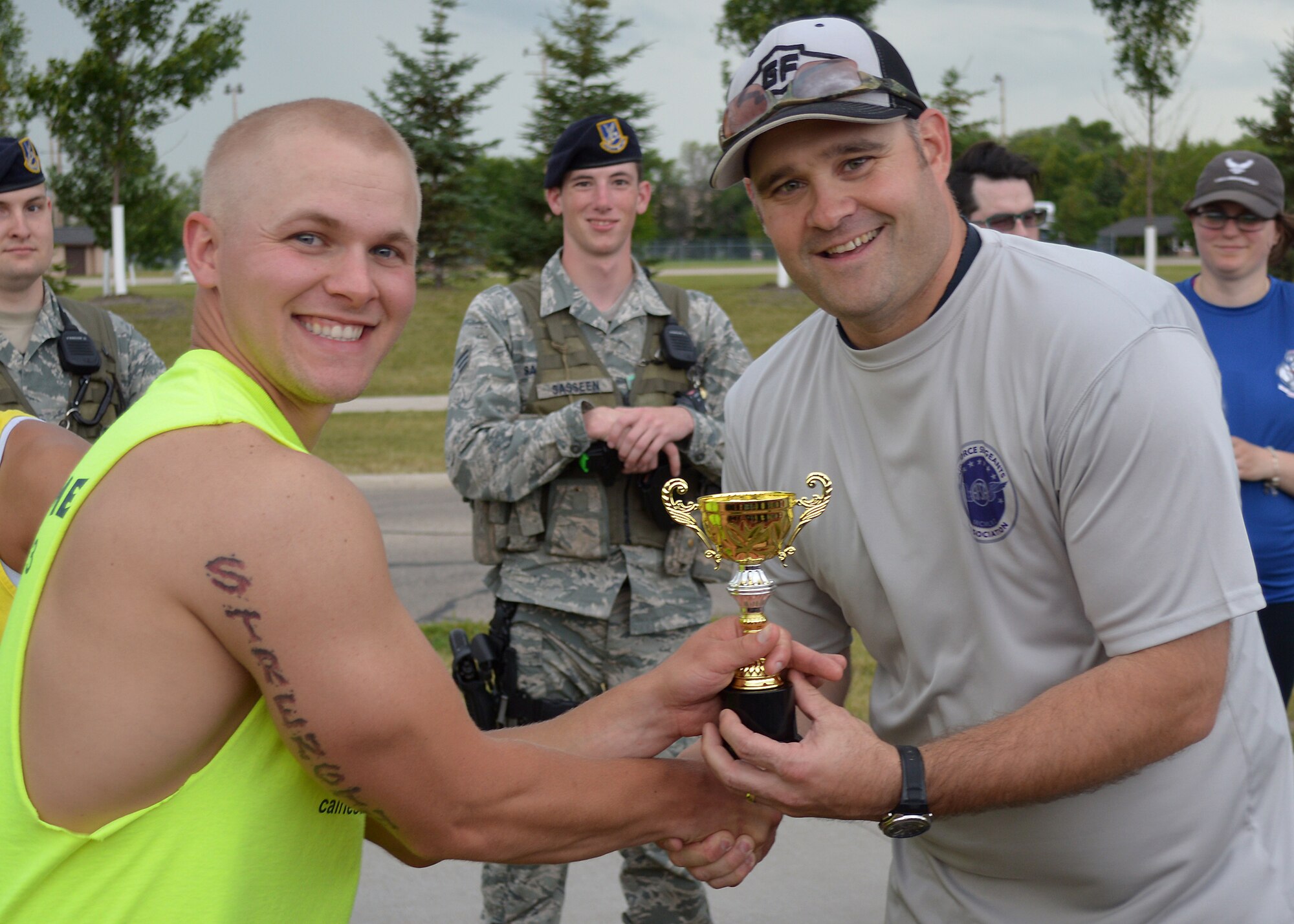 (Right) Tech. Sgt. Jared Langenstein, Air Force Sergeants Association, Chapter 964 president, hands the first-place trophy to Senior Airman Benjamin Crawley, 319th Communications Squadron, for winning the team category during the 12-hour relay on July 18, 2014, on Grand Forks Air Force Base, N.D. The Misfits team completed 86 laps around the base outdoor running track during the relay, which helped raise money for the Wounded Warrior Project and the local Air Force Sergeants Association. (U.S. Air Force photo/Senior Airman Xavier Navarro) 