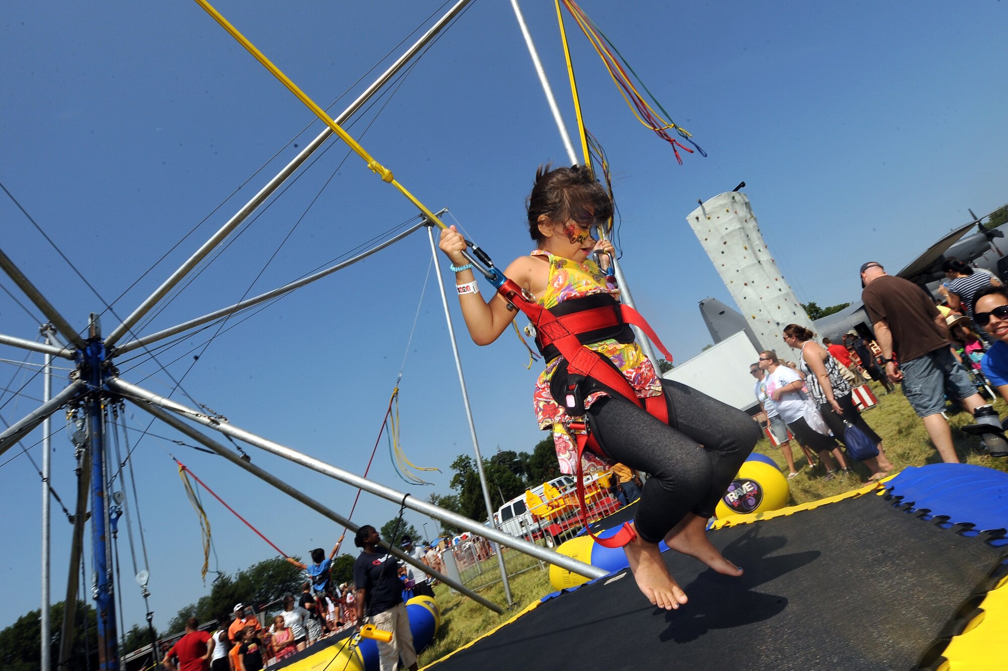 Six-year-old Alisiana Gomez, daughter of Taylor Gomez, launches herself into the sky with bungee cables and a trampoline while attending the 2014 Defenders of Freedom Open House and Air Show July 20 at Offutt Air Force Base, Nebraska.  Record crowds attended this year’s event.  (U.S. Air Force photo by Josh Plueger/Released)
