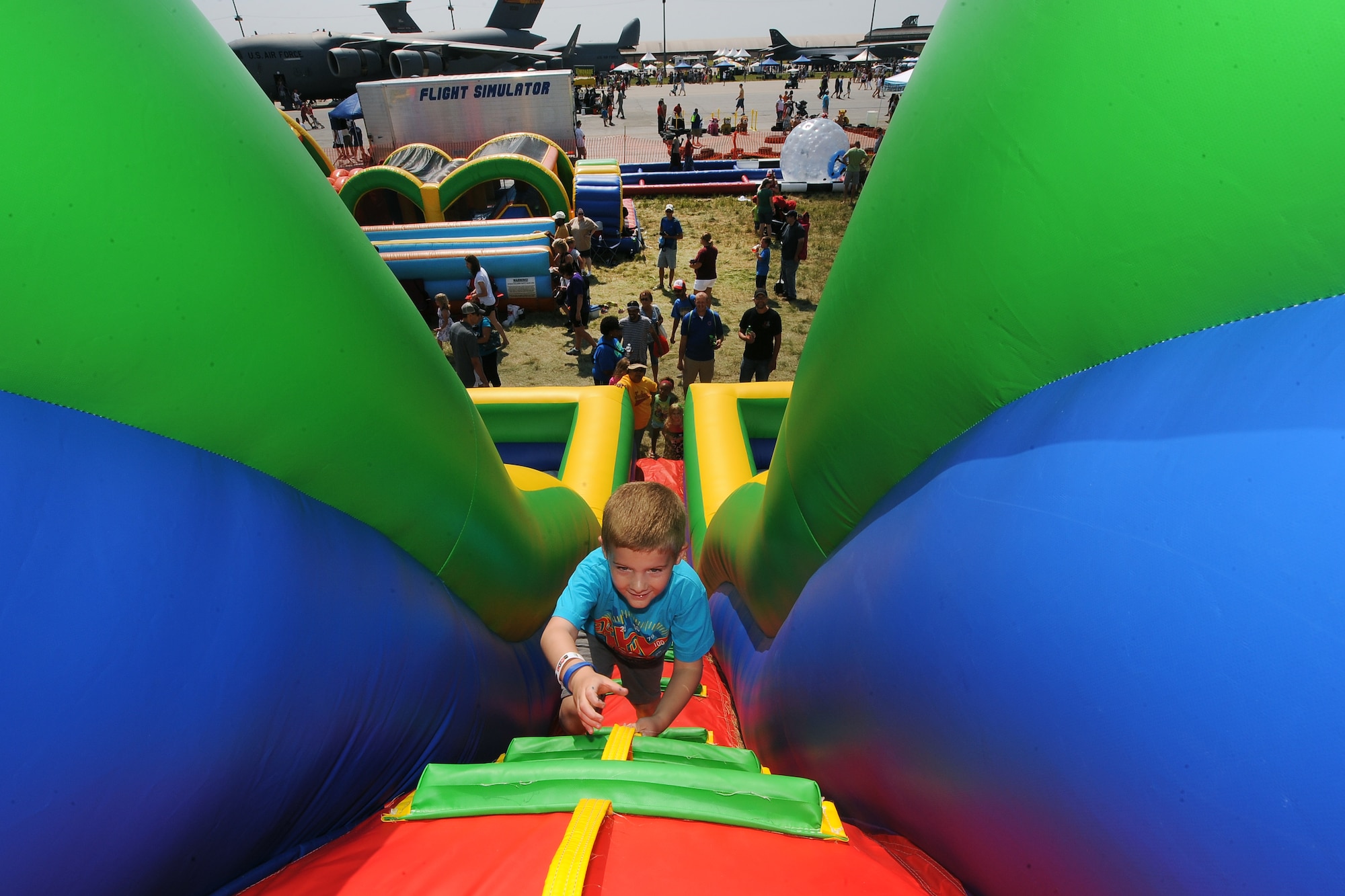 Six-year-old Liam Stieren, from Omaha, climbs to the top of a large inflatable slide at the 2014 Defenders of Freedom Open House and Air Show July 20 at Offutt Air Force Base, Nebraska.  This year the Offutt air show had a larger area dedicated to kids’ activities in conjunction with the open house.  (U.S. Air Force photo by Josh Plueger/Released)