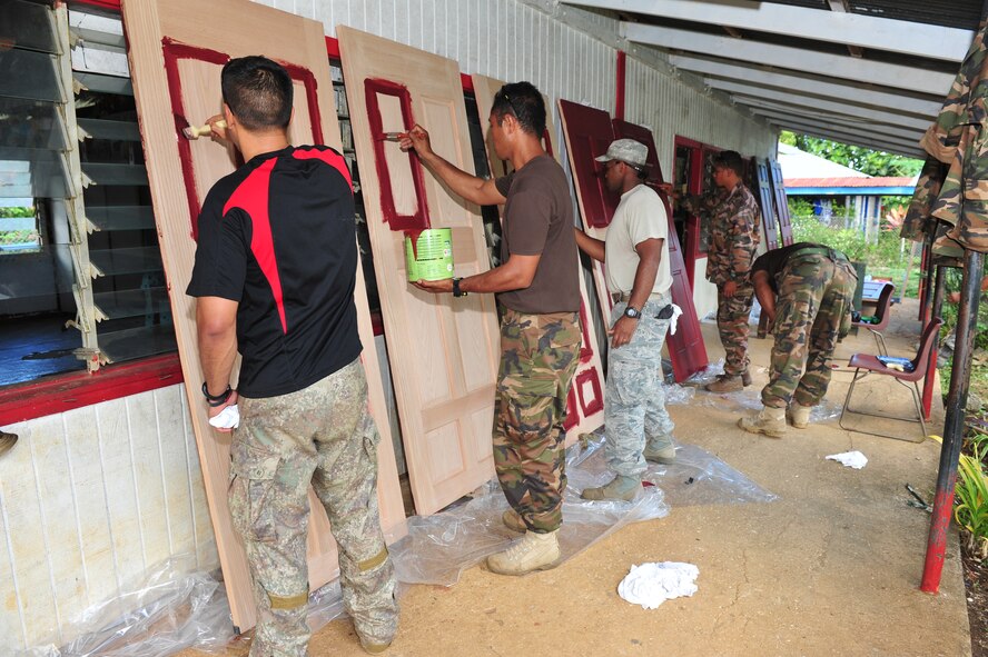 Kiwi, Tongan, and American military members paint doors at Toula Government Primary School, Toula, Vava'u, July 17, 2014. Military members make several repairs at five schools including the replacement of doors, locks, windows, wiring, partitions, sinks, faucets and toilets during Operation Pacific Angel-Tonga. (U.S. Air Force photo by Staff Sgt. Rachelle Coleman)