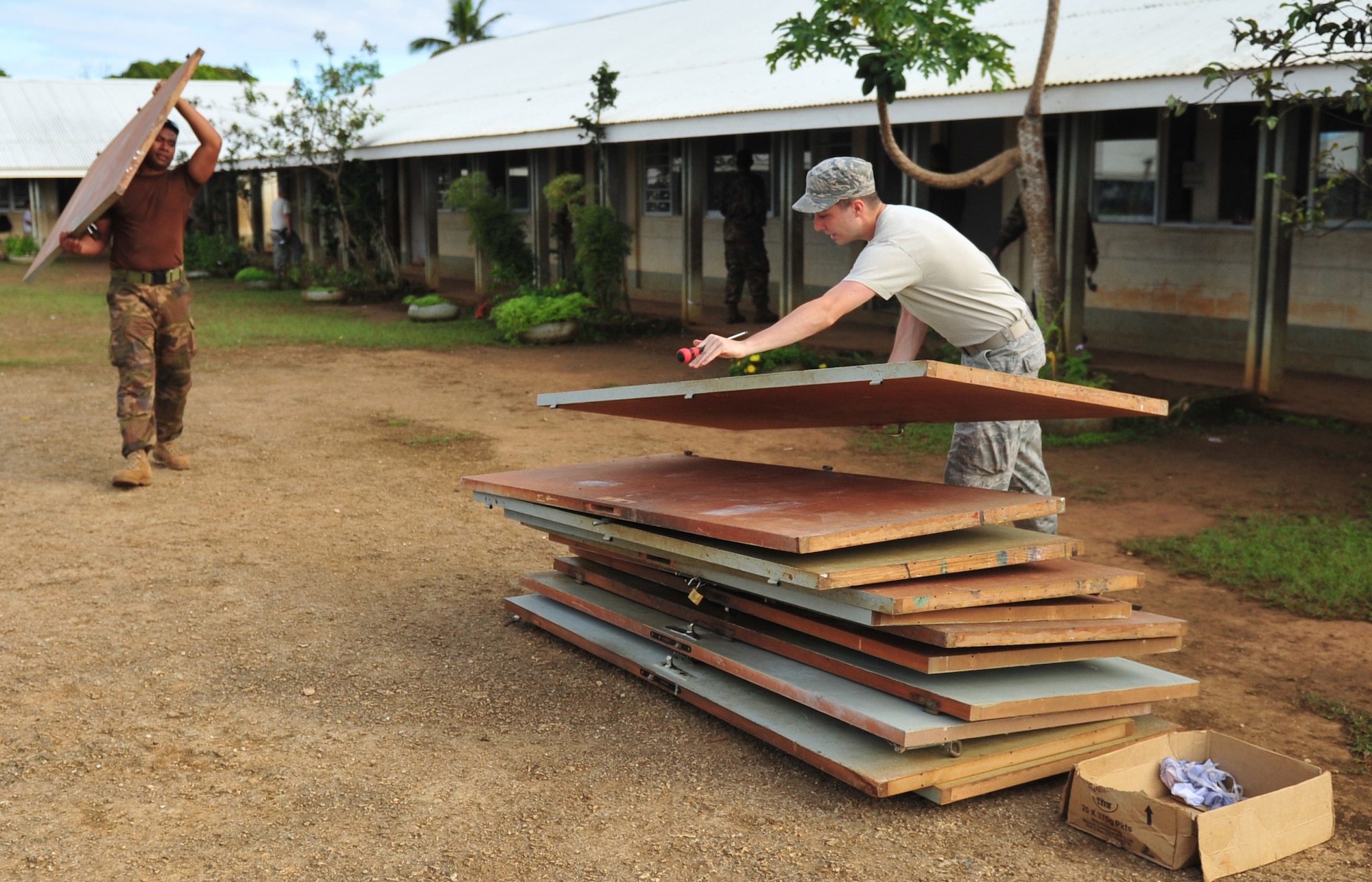U.S. Air Force Airman 1st Class Devin Laird, Pacific Angel electrician, places an old door on the pile at Neiafu Government Primary School, Neiafu, Vava'u, July 17, 2014. Military electricians, structural craftsmen, carpenters and plumbers are worked together to repair and replace doors, locks, windows, wiring, partitions, sinks, faucets, toilets and various additional requirements during the operation. Laird is deployed from the 374th Civil Engineer Squadron, Yokota Air Base, Japan. (U.S. Air Force photo by Staff Sgt. Rachelle Coleman)