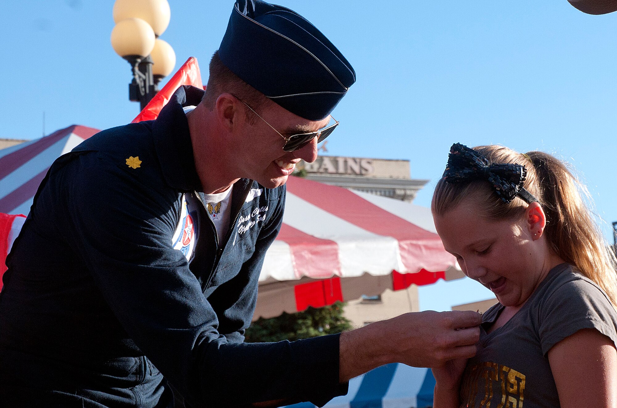 Maj. Jason Curtis, U.S. Air Force Thunderbirds pilot, gives Allie Robert, 10, a Thunderbirds pin July 21 before sitting down to sign autographs at the Cheyenne Depot Plaza.  The Thunderbirds use community outreach events, such as the breakfast, to accomplish three missions: recruit, represent and retain. (U.S. Air Force photo by Airman Malcolm Mayfield)