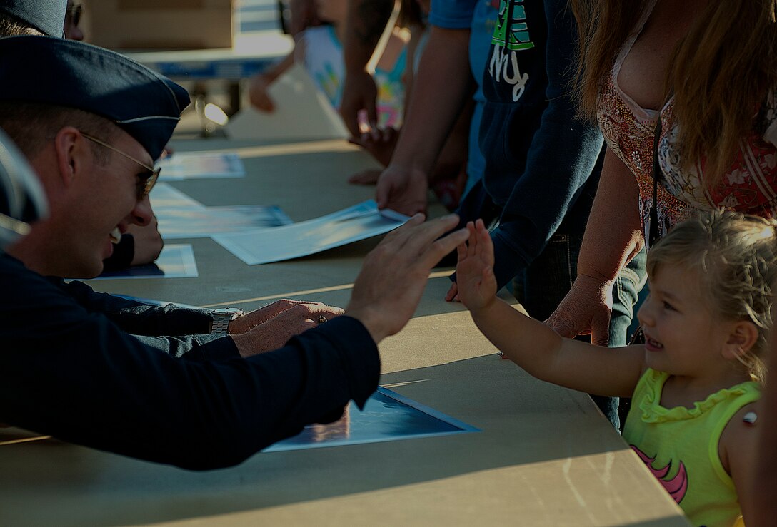 Maj. Jason Curtis, U.S. Air Force Thunderbirds pilot, gives a high-five to Payton Rutherford, 3, during an autograph session July 21 at the Cheyenne Depot Plaza. The pilot spent about 40 minutes interacting with the community during the session. (U.S. Air Force photo by Airman 1st Class Brandon Valle)