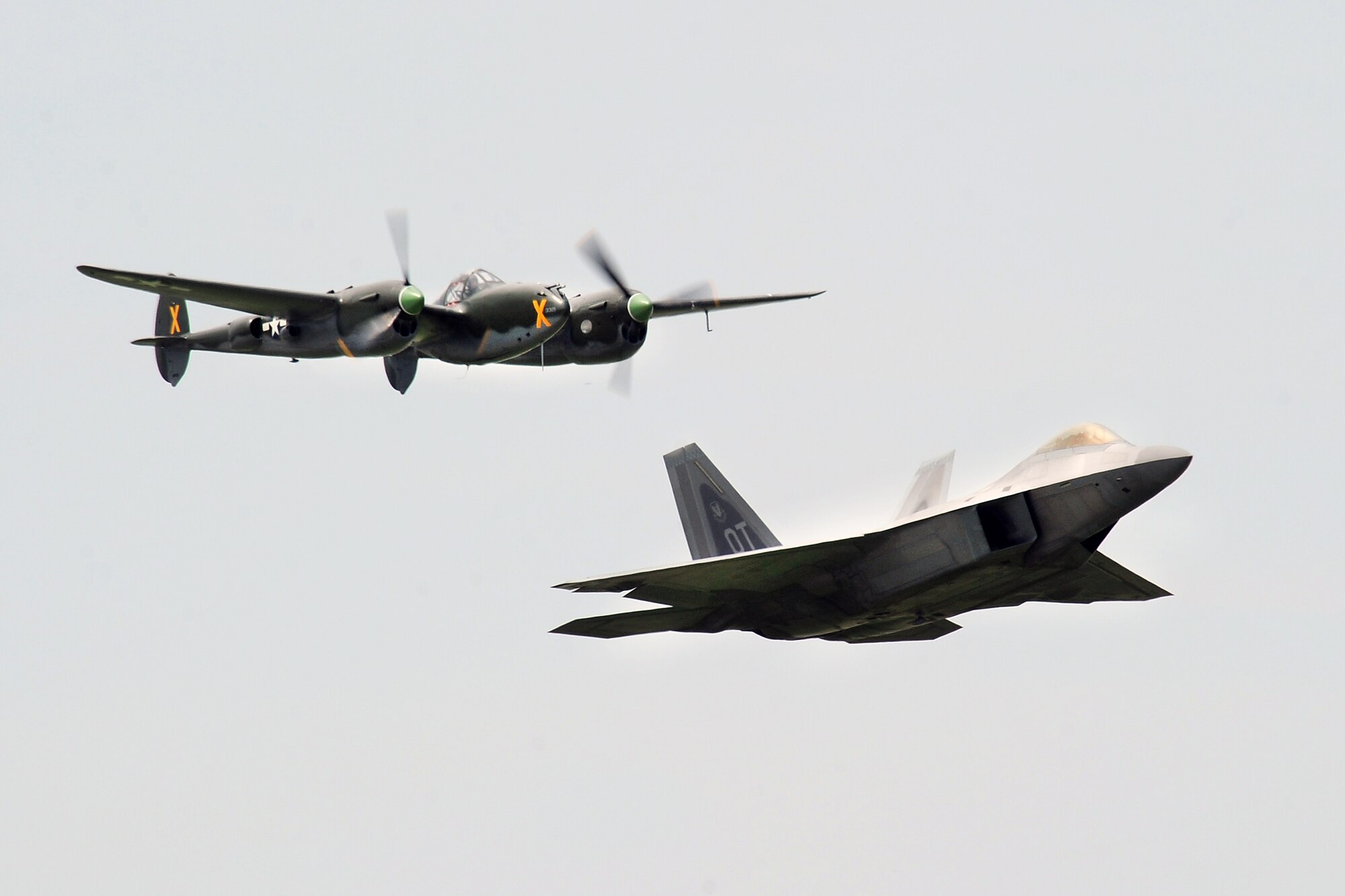 A P-38 Lightning performs side-by-side with an F-22 Raptor for a heritage flight at the 2014 Defenders of Freedom Open House and Air Show July 19 at Offutt Air Force Base, Nebraska.   The air show hosted 12 performers with the U.S. Air Force F-22 Demo Team and the U.S. Navy Blue Angels being the headliners of the event.  (U.S. Air Force photo by Josh Plueger/Released) 