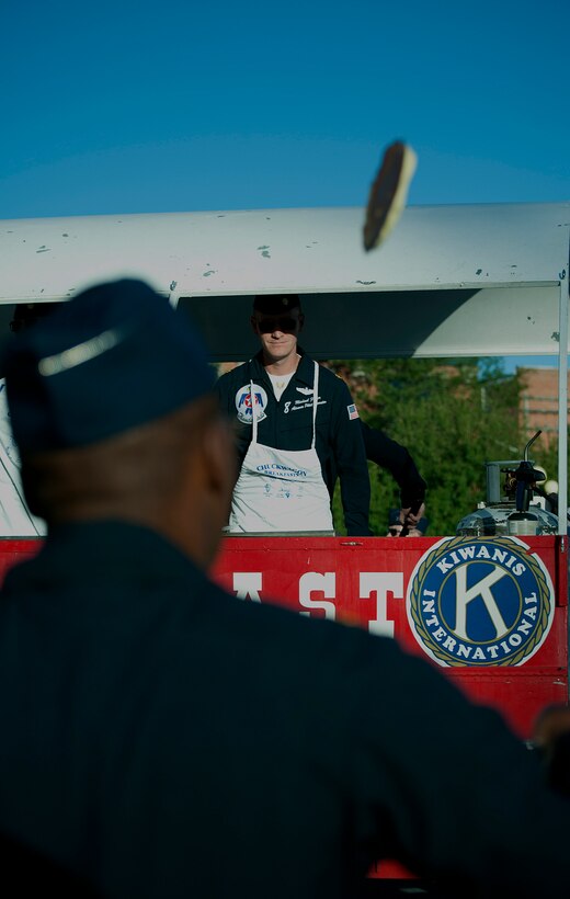 Maj. Michael Fisher, U.S. Air Force Thunderbirds pilot, flips a pancake to Maj. Darrick Lee, U.S. Air Force Thunderbirds Public Affairs officer, July 21 during the annual pancake breakfast at the Cheyenne Depot Plaza. The Thunderbirds joined community members in making pancakes for the breakfast. (U.S. Air Force photo by Airman 1st Class Brandon Valle)