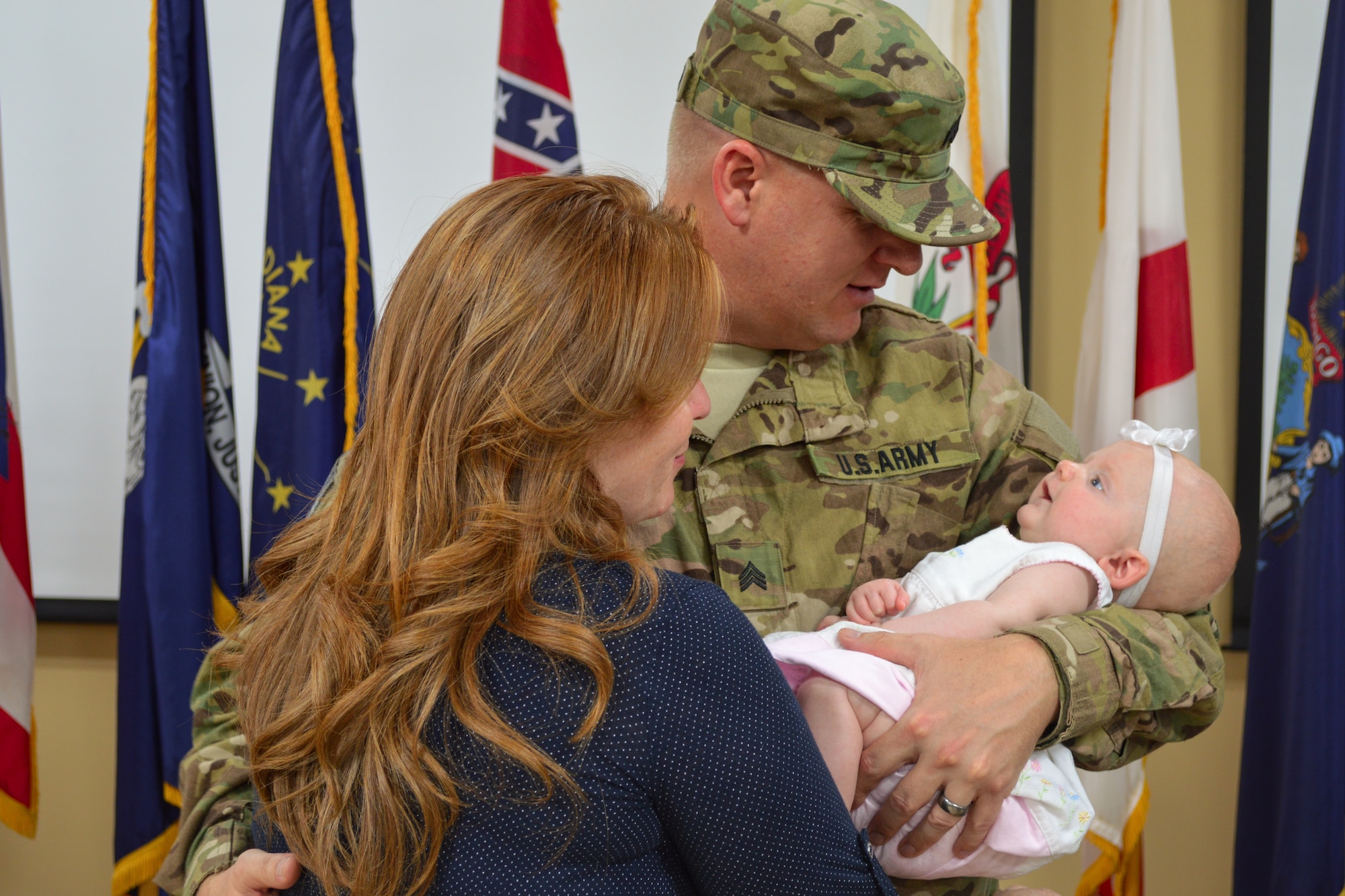 U.S. Army Sgt. John Kennerson with the 612th Movement Control Team, 53rd Transportation Battalion, 7th Transportation Brigade (Expeditionary), embraces his family during a deployment ceremony at Fort Eustis, Va., July 19, 2014.  Kennerson’s 3-month-old daughter, Claire, is one of eight children. (U.S. Army photo by Spc. Marian Alleva/Released) 