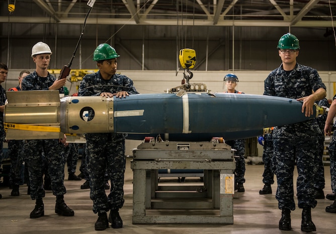 Navy Munitions Command mine shop minemen move a training mine from a table to a pallet on the floor during an exercise July 16, 2014, at Joint Base Charleston, S.C. The Sailors in the mine shop routinely conduct drills and exercises to maintain their qualifications so they will be ready to deploy if necessary. (U.S. Air Force photo by Senior Airman Dennis Sloan)