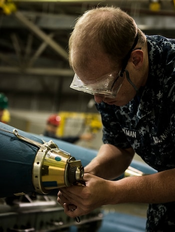 Petty Officer 3nd Class Brian Steelamn, Navy Munitions Command mineman, works on mines during an exercise July 16, 2014, at Joint Base Charleston, S.C. The Sailors in the mine shop routinely conduct drills and exercises to maintain their qualifications so they will be ready to deploy if necessary. (U.S. Air Force photo by Senior Airman Dennis Sloan)