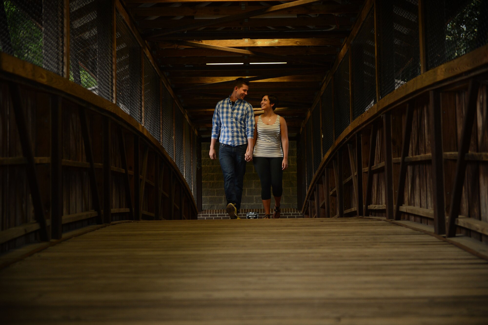U.S. Air Force Airmen 1st Class, Michael and Diana Cossaboom, 20th Fighter Wing Public Affairs photojournalists, walk across a bridge at Swan Lake and Iris Gardens near Shaw Air Force Base, S.C., July 19, 2014. The Cossabooms participated in a six week marriage mentorship program created by Chaplain (Maj.) Richard Holmes, 20th FW interim deputy wing chaplain, which helped the two learn about their “love languages”. (U.S. Air Force photo by Airman 1st Class Jensen Stidham/Released)