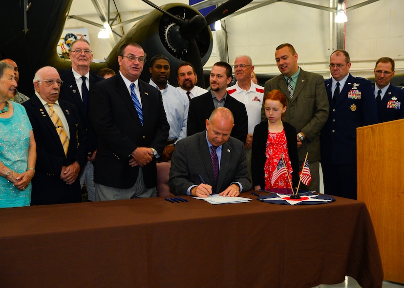 Delaware Governor Jack Markell, sitting, signs Delaware House Bills 296 and 324 at a ceremony July 21, 2014, at the Air Mobility Command Museum on Dover Air Force Base, Del. HB 296 allows professional licensing boards to recognize military education, training and experience when reviewing credentials and issuing licenses and aims to assist service personnel and their spouses in obtaining and/or renewing professional licenses when transitioning from active duty. HB 324 creates a special motor vehicle license plate for the purpose of honoring Delaware’s veterans. (U.S. Air Force photo/Airman 1st Class Zachary Cacicia)