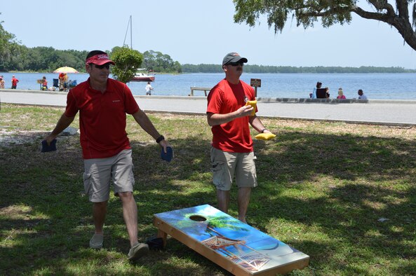 Dave Brunnette (left) and Master Sgt. Michael White of Air Forces Northern’s Intelligence Directorate, toss bean bags during AFNORTH Family Day June 27 at Bonita Bay. (Photo by Mary McHale)