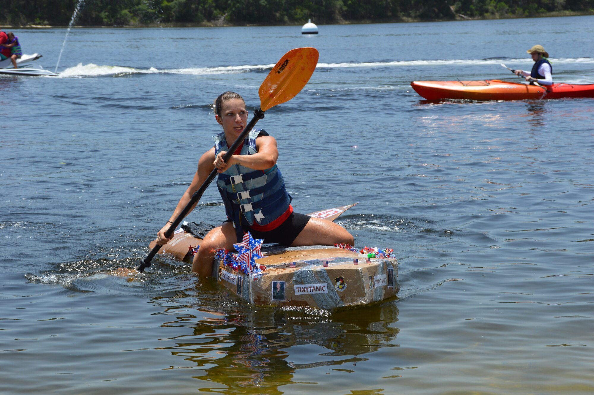Staff Sergeant Kerry Wilder of Air Forces Northern’s Operations Directorate navigates the directorate’s entry, the “SS Wimmer,” during the cardboard boat race at AFNORTH Family Day June 27 at Bonita Bay. (Photo by Mary McHale)