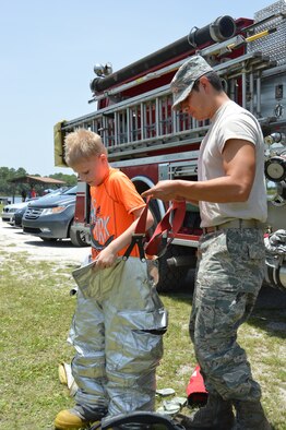 A young visitor to Air Forces Northern Family Day gets some assistance checking out firefighting equipment. The day was held at Bonita Bay June 27 and featured a variety of food and activities. (Photo by Mary McHale) 

