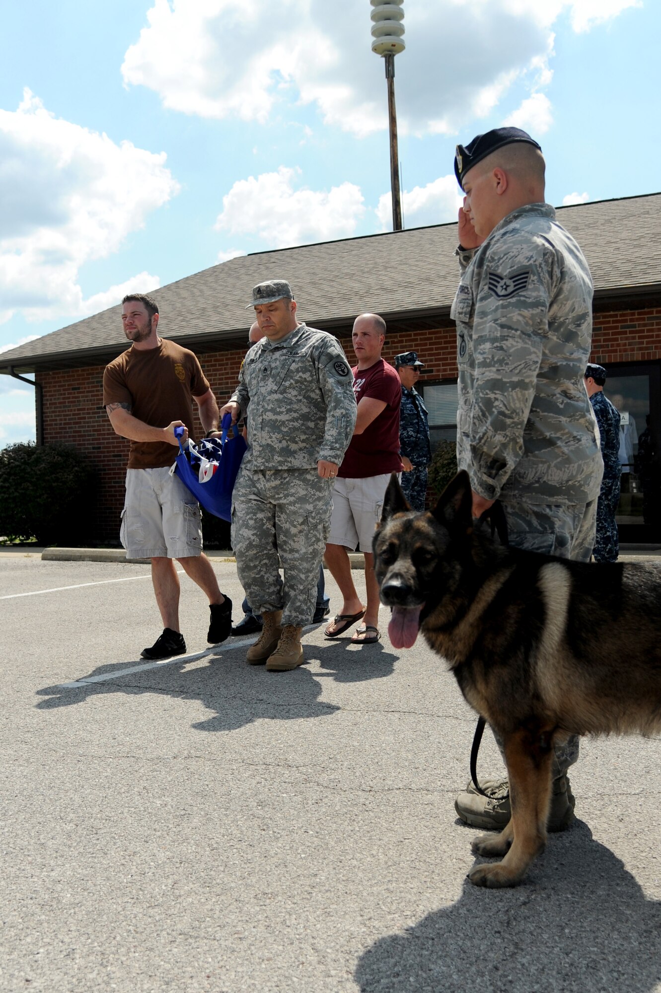 A 375th Security Forces member renders a final salute to Military Working dog Brix and his handler, Master at Arms Drew Risley, as they make their way out of the vets office to give him a military honors July 18, 2014 at Scott Air Force Base, Ill. Brix's health took a turn for the worse when he started having hip problems. Brix was awarded a Navy Marine Corp Achievement medal and an Army Commendation medal while being deployed in Iraq. He retired in 2011 upon returning from a deployment. (U.S Air Force photo/ Senior Airman Tristin English)