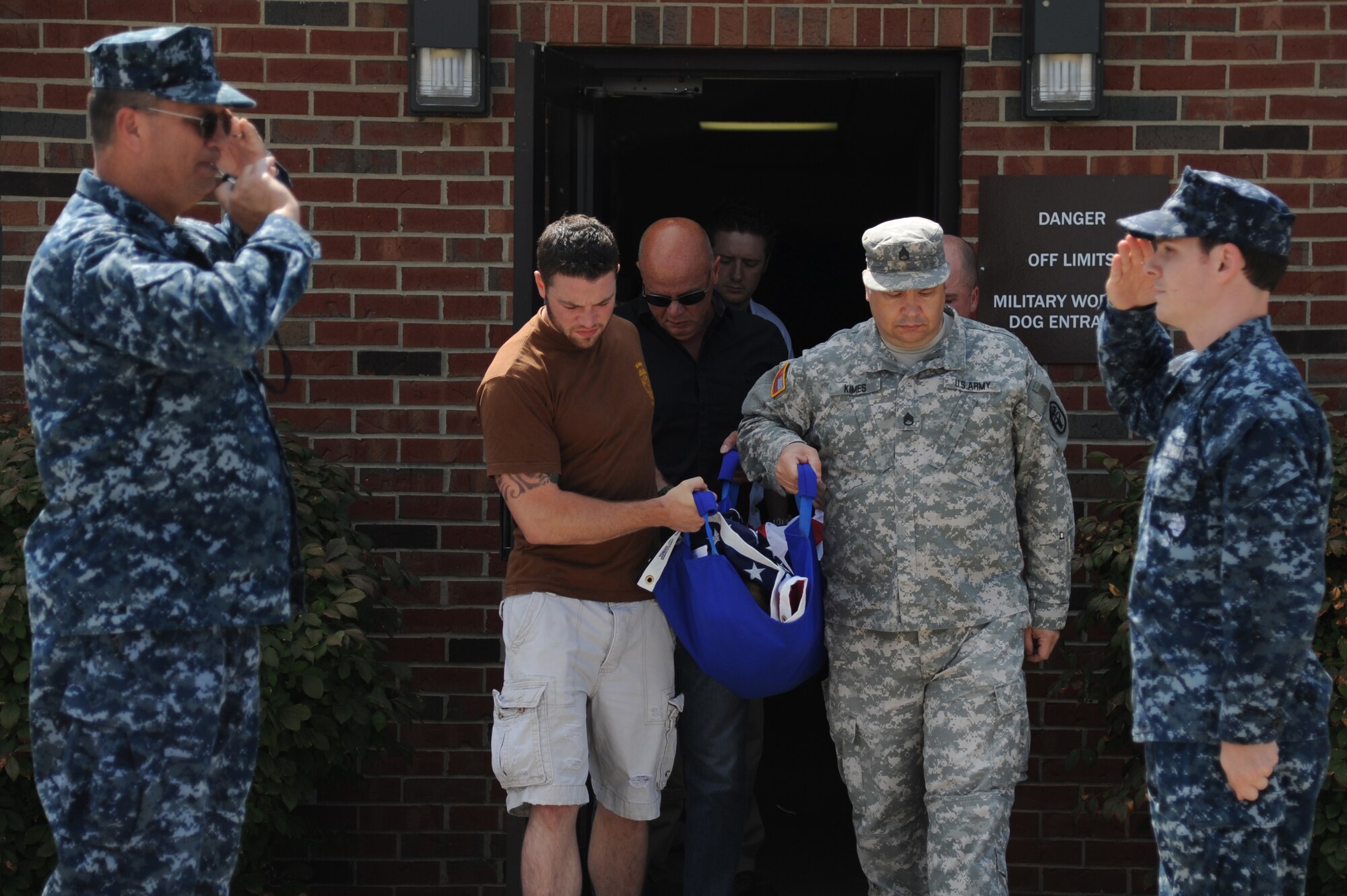 The United States Navy renders a final salute to Military Working dog Brix and his handler, Master at Arms Drew Risley, as they make their way out of the vets office to give him a military honors July 18, 2014 at Scott Air Force Base, Ill. Brix's health took a turn for the worse when he started having hip problems. Brix was awarded a Navy Marine Corp Achievement medal and an Army Commendation medal while being deployed in Iraq. He retired in 2011 upon returning from a deployment. (U.S Air Force photo/ Senior Airman Tristin English)