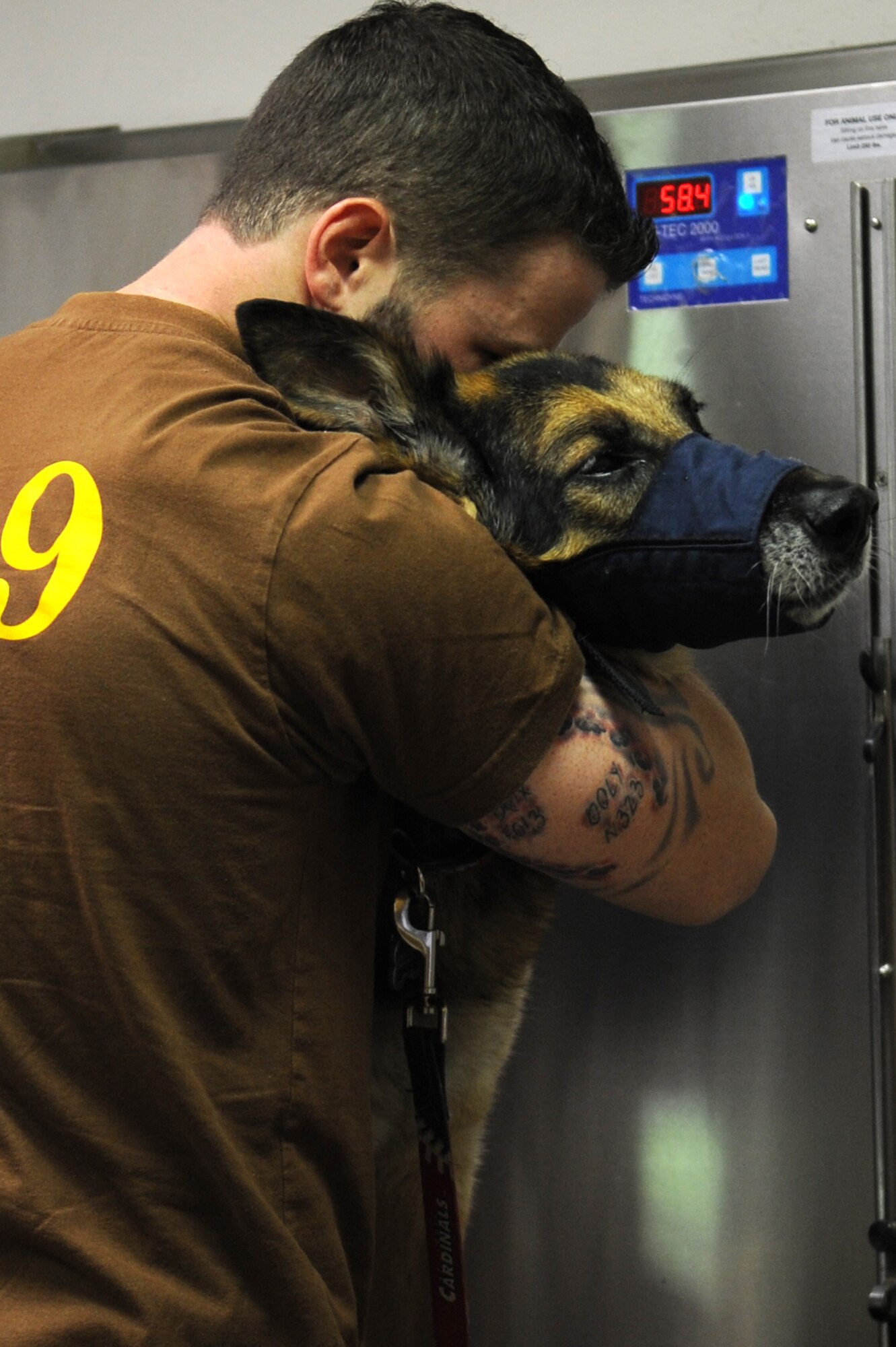 Handler Master at Arms Drew Risley comforts Military working dog Brix before being sedated July 18, 2014 at Scott Air Force Base, Ill. Brix's health took a turn for the worse when he started having hip problems. Brix was awarded a Navy Marine Corp Achievement medal and an Army Commendation medal while being deployed in Iraq. He retired in 2011 upon returning from a deployment. (U.S Air Force photo/ Senior Airman Tristin English)