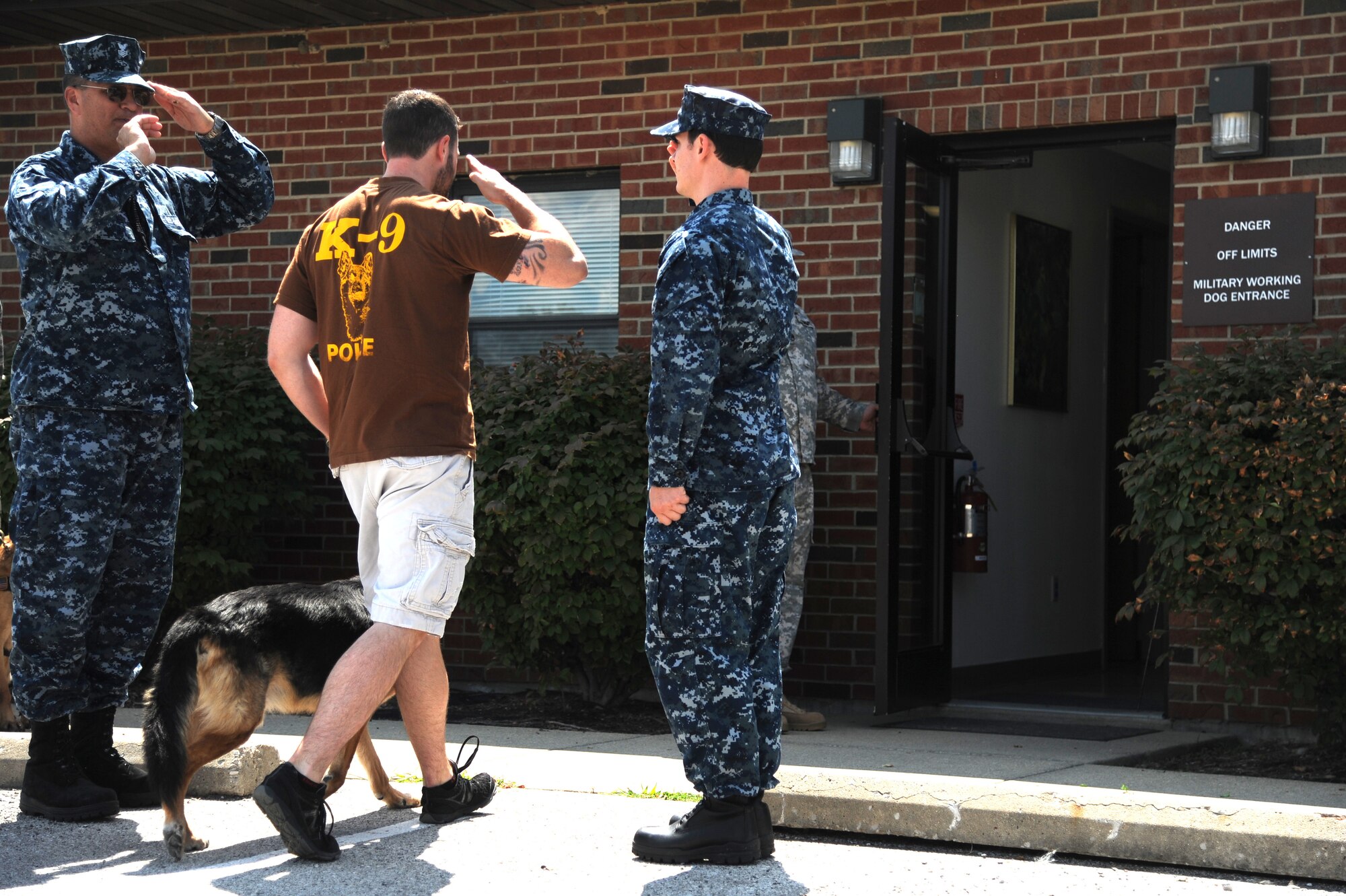 The United States Navy renders a salute to Military Working dog Brix and his handler, Master at Arms Drew Risley, as they make their way into the vets office July 18, 2014 at Scott Air Force Base, Ill. Brix's health took a turn for the worse when he started having hip problems. Brix was awarded a Navy Marine Corp Achievement medal and an Army Commendation medal while being deployed in Iraq. He retired in 2011 upon returning from a deployment. (U.S Air Force photo/ Senior Airman Tristin English)