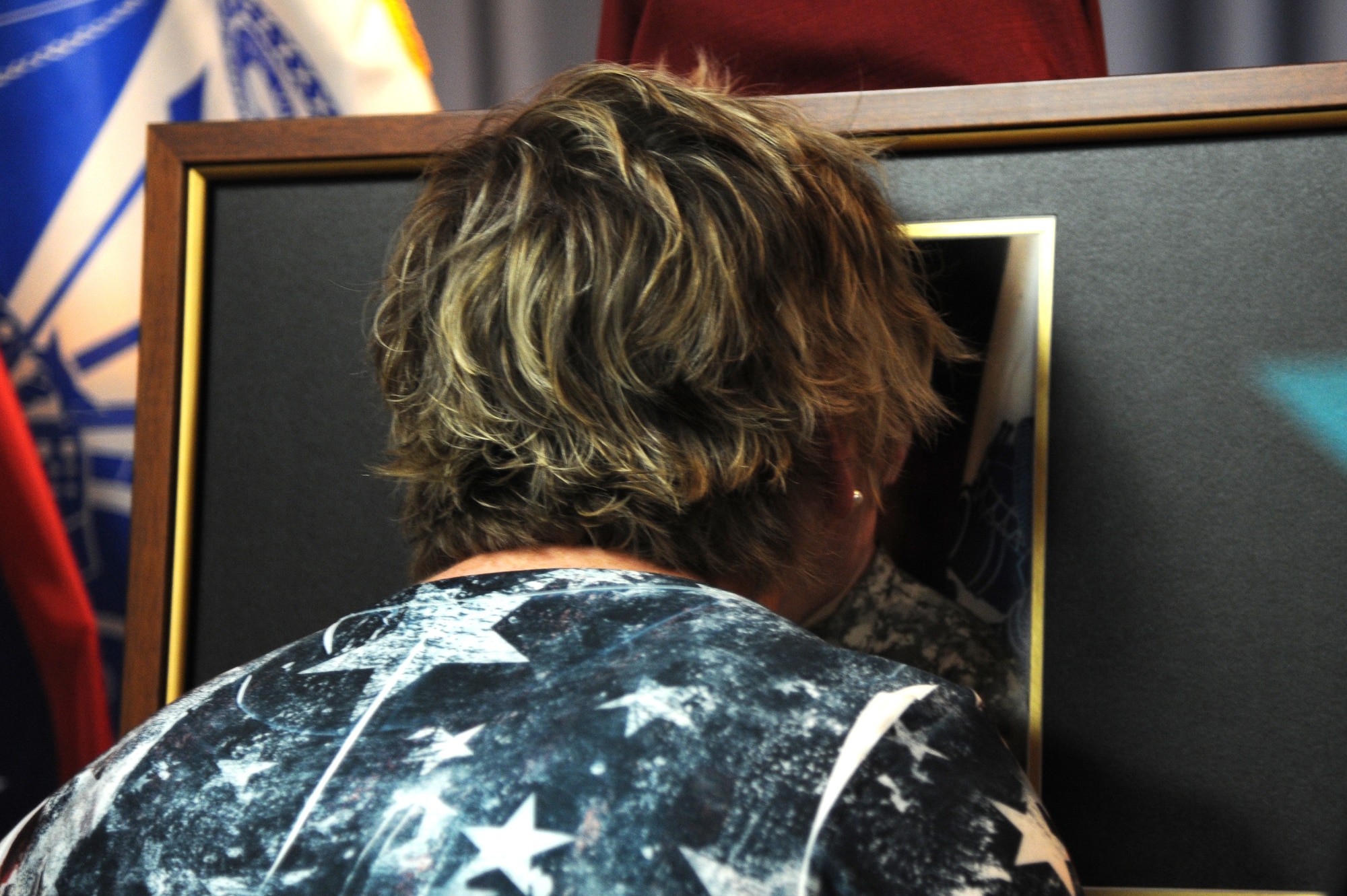 Sherry Wyatt gives a kiss to a photo of U.S Army Specialist Sterling Wyatt during a dedication ceremony at the St. Louis Military Entrance Processing Station in St. Louis, MO, July 17, 2014. Sterling Wyatt was killed in action when his vehicle was attacked with an enemy improvised explosive device. Wyatt received the Medal of Valor,Combat Infantry Badge and the Bronze Star. (U.S. Air Force photo/Senior Airman Tristin English)
