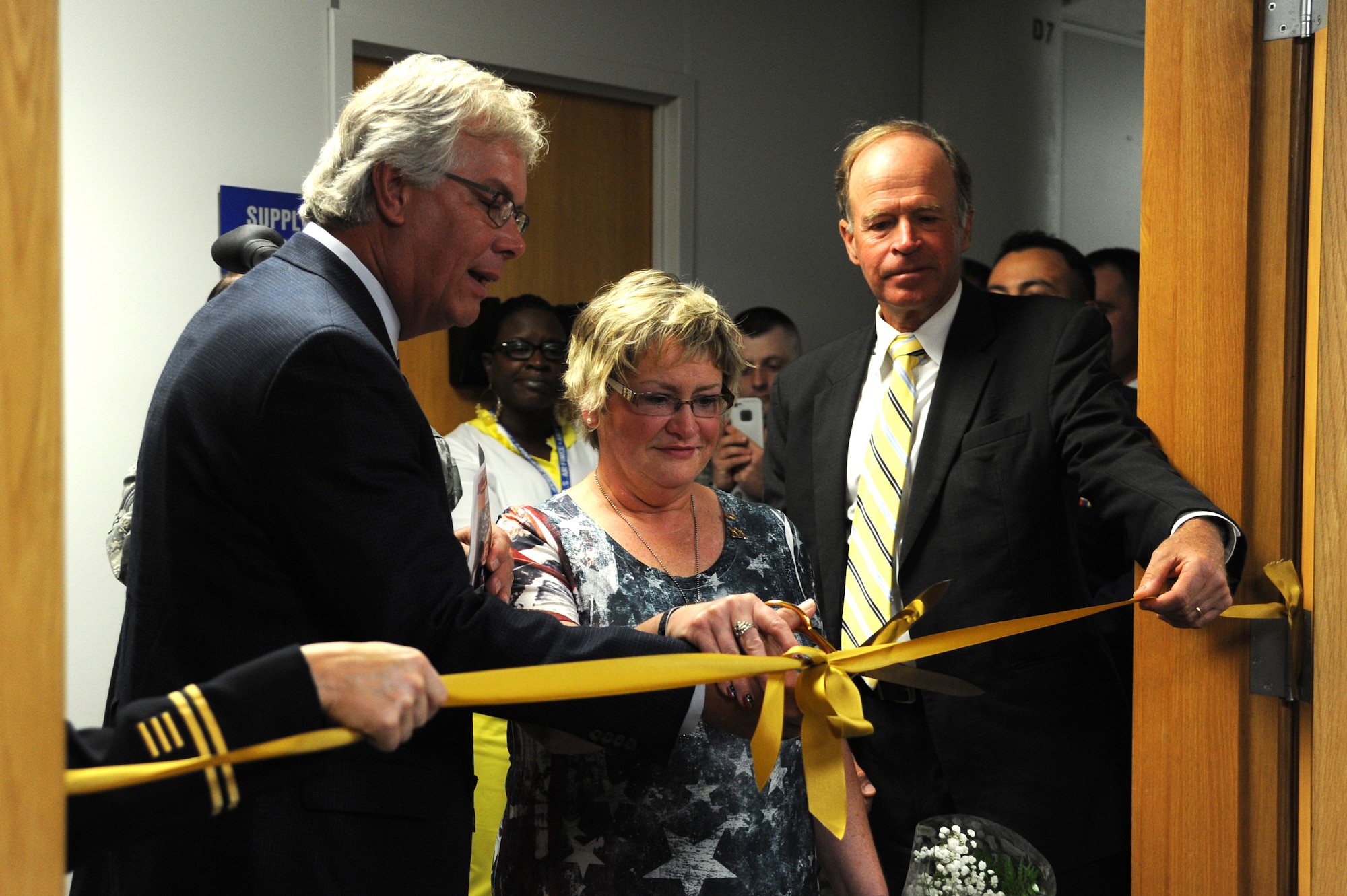 Sherry and Randy Wyatt and Bob McDavid, the Mayor of Columbia, MO, cut the yellow ribon during the dedication ceremony of U.S Army Specialist Sterling Wyatt dedication ceremony at the St. Louis Military Entrance Processing Station in St. Louis, MO, July 17, 2014. The cutting of the yellow ribbon symbolized the renaming of the room. (U.S. Air Force photo/Senior Airman Tristin English)