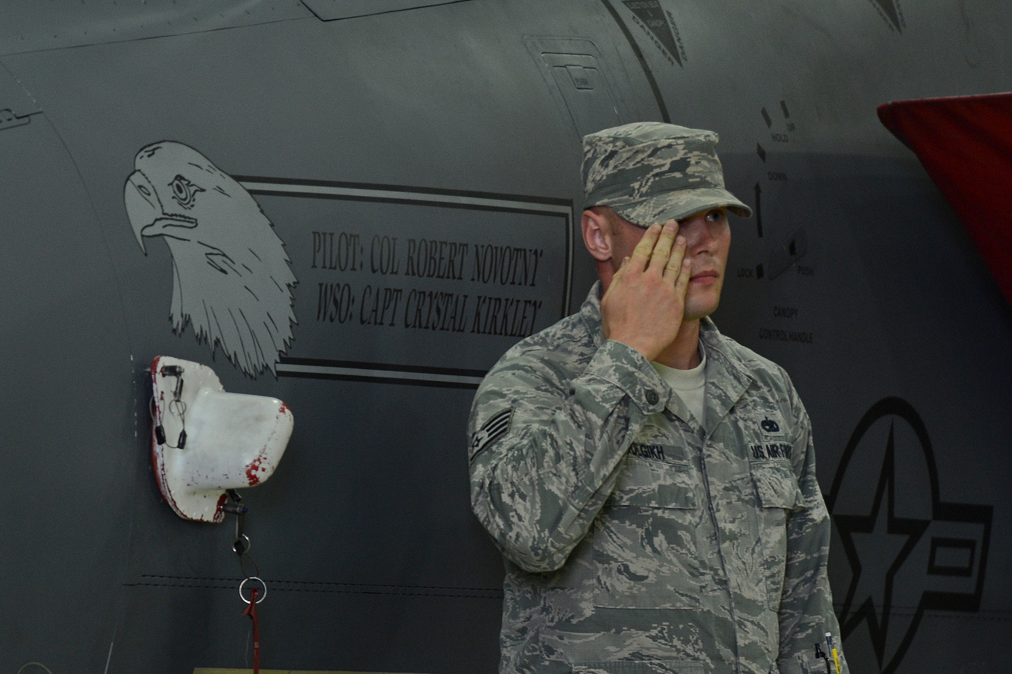 Staff Sgt. Aleksandr Dolgikh, 48th Aircraft Maintenance Squadron dedicated crew chief, reveals the new commander’s name on an F-15E Strike Eagle during the 48th Fighter Wing change of command ceremony in Hangar 7 at Royal Air Force Lakenheath, England , July 21, 2014. (U.S. Air Force photo by Airman 1st Class Trevor T. McBride/Released)