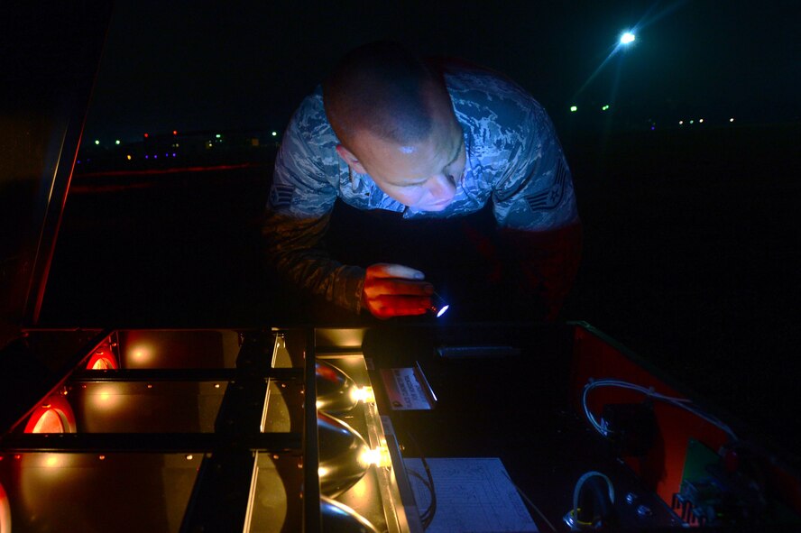 U.S. Air Force Staff Sgt. Nicholes Crumb, 20th Civil Engineer Squadron electrical systems craftsman, inspects a precision approach path indicator light on the runway at Shaw Air Force Base, S.C., July 16, 2014. Without each of the four main lights inside, the PAPI would not be able to accurately tell pilots their correct altitude for a safe landing during low-light conditions. (U.S. Air Force photo by Airman 1st Class Jensen Stidham/Released)