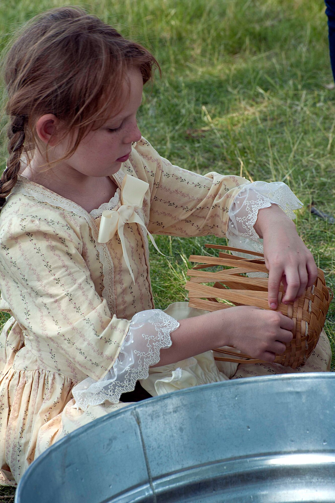 Barbara Evans, 8, weaves a basket July 18 during the annual F.E. Warren Air Force Base open house, Fort D.A. Russell Days. Re-enactors perform daily tasks as they were performed during the colonial era of the U.S., including cooking, crafts and entertainment. (U.S. Air Force photo by Airman 1st Class Brandon Valle)