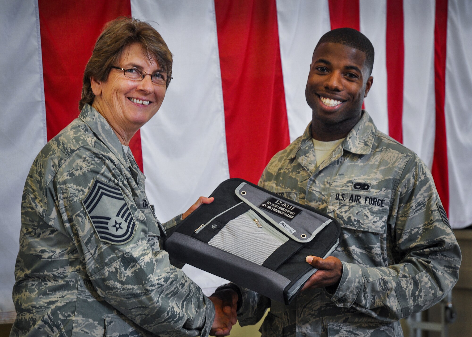 Staff Sgt. Brandon Walker, of the 592nd Special Operations Maintenance Squadron, accepts his aircraft binder as an assistant crew chief from Chief Master Sgt. Pamela Duvall, of the 919th Special Operations Maintenance Squadron during the crew chief aircraft assignment ceremony at Duke Field, June 11. The 592nd and the 919th assigned a dedicated crew chief and assistant crew chief to each of the 16 C-145s at Duke Field.  Each aircraft has an active-duty and reserve crew chief assigned to it.  The squadrons took over maintenance responsibility for the aircraft on July 1.  (U.S. Air Force photo/Dan Neely)