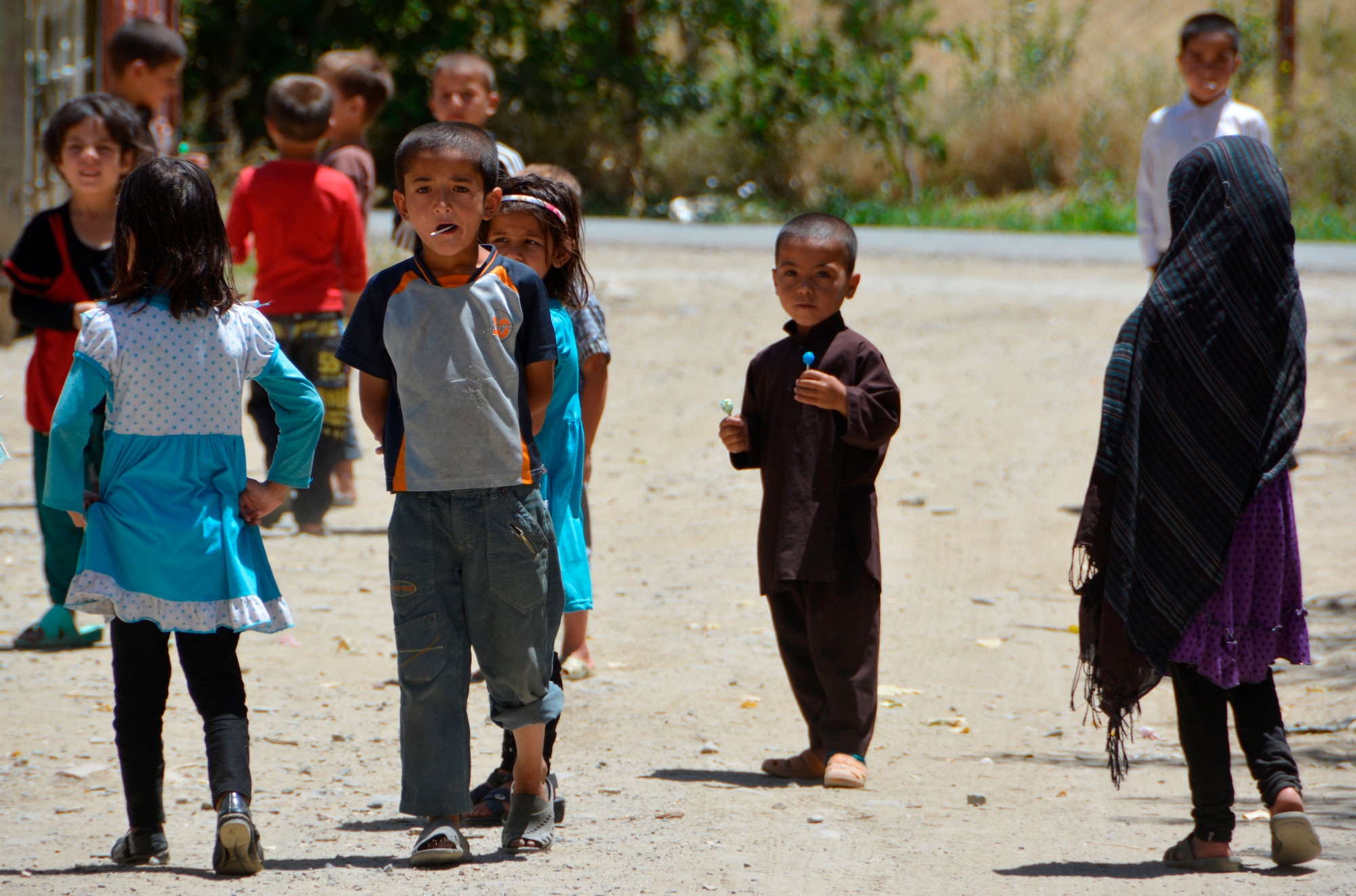 Afghan children enjoy lollipops after twelve members of the International Security Assistance Forces delivered more than 800 pounds of donated clothing, toys, and school supplies to Afghan children at a residential compound near Kabul, Afghanistan July 18. (U.S. Air Force photo by Lt. Col. James Bishop, ISAF HQ)
