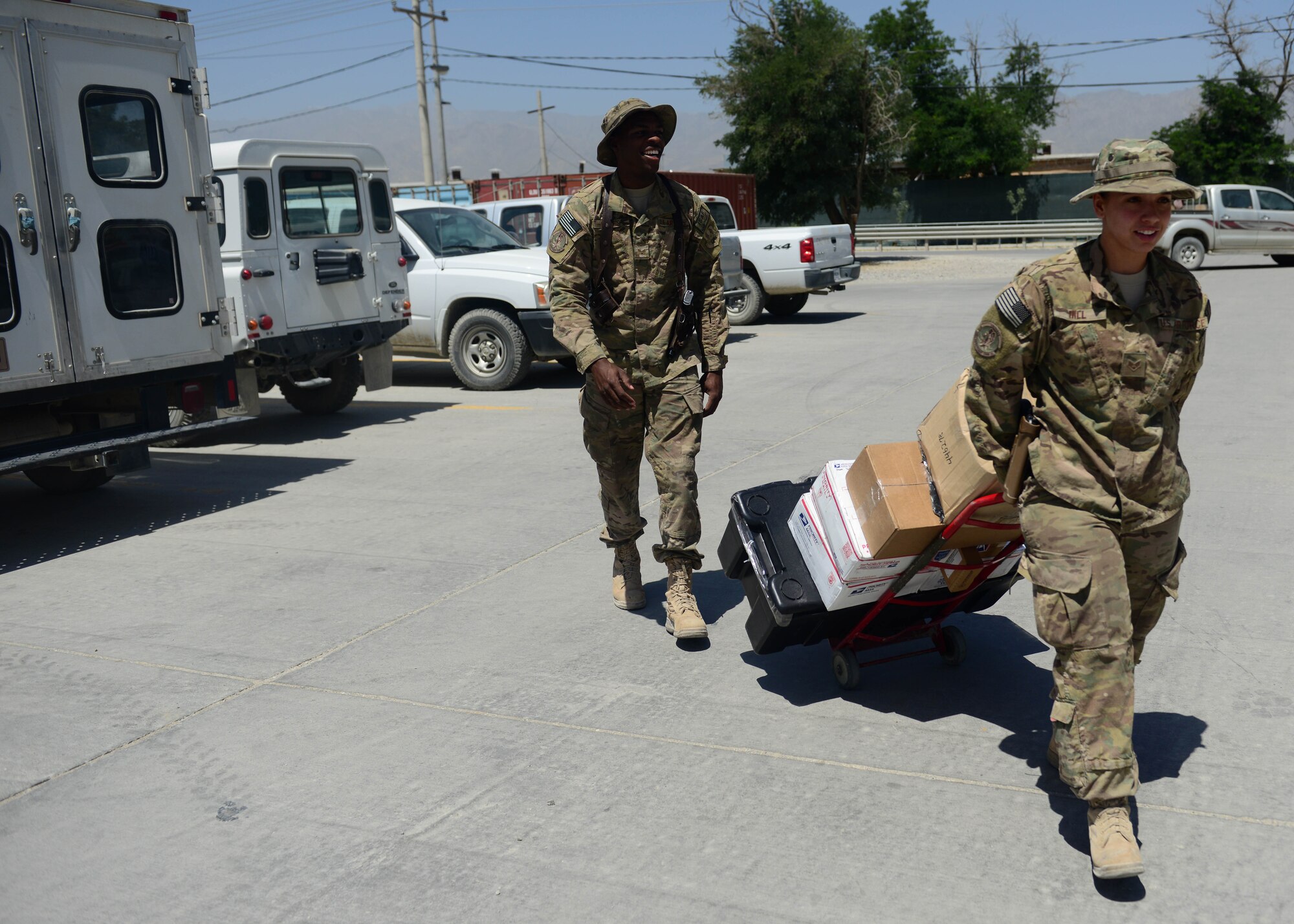 (From left) U.S. Air Force Senior Airmen Lorenza Kates and Victoria Hill, 455th Expeditionary Communications Squadron mail clerks deliver mail at Bagram Airfield, Afghanistan June 26, 2014.  Kates and Hill are responsible for handling mail for Airmen in the 455th Air Expeditionary Wing. They handle thousands of packages and letters per month.  Kates is deployed from Davis Monthan Air Force Base, Ariz. and a native of Dublin, Ga. Hill is deployed from Whiteman Air Force Base, Mo. and a native of Blanchard, La.  (U.S. Air Force photo by Staff Sgt. Evelyn Chavez)