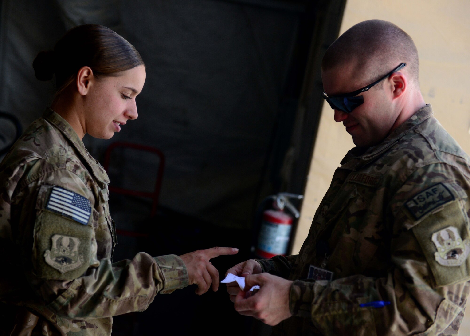 (Left) U.S. Air Force Senior Airman Victoria Hill, 455th Expeditionary Communications Squadron mail clerk verifies a customer is allowed to pick up mail at Bagram Airfield, Afghanistan June 25, 2014.  Hill is responsible for handling mail for Airmen assigned to the 455th Air Expeditionary Wing.  She handles thousands of packages and letters per month. Hill is deployed from Whiteman Air Force Base, Mo. and a native of Blanchard, La.  (U.S. Air Force photo by Staff Sgt. Evelyn Chavez)