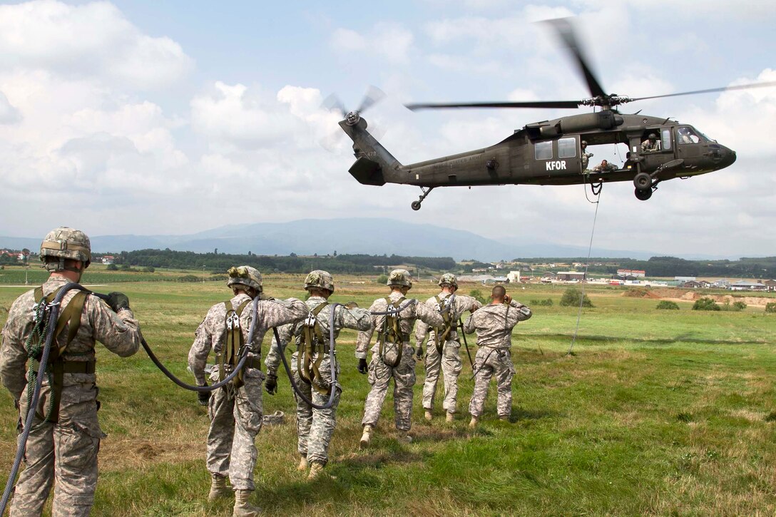 U.S. soldiers line up and prepare to be hoisted on a fast-rope line hooked up to a UH-60 Black Hawk helicopter during training on Camp Bondsteel, Kosovo, July 18, 2014. The soldiers, assigned to the 2nd Squadron, 38th Cavalry Regiment, 504th Battlefield Surveillance Brigade, are participating in fast-rope insertion and extraction training, and are employed by small units to make rapid infiltration and exfiltration using rotary-wing aircraft in confined areas.