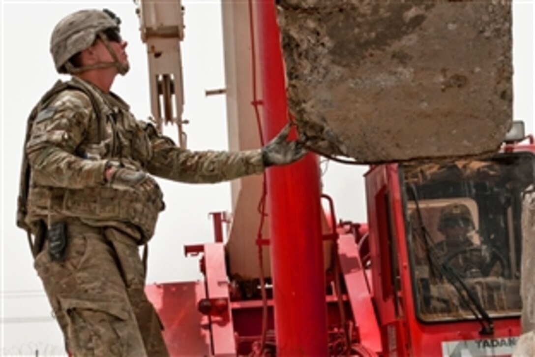 U.S. Army Pvt. Tyler Garlitz, left, and U.S. Army Sgt. Juan Mendoza hoist one of the last concrete barriers onto a trailer during base closure operations on Forward Operating Base Walton in Afghanistan's Kandahar province, July 16, 2014. Garlitz and Mendoza are heavy equipment operators assigned to the 687th Engineer Company, 46th Engineer Battalion, 1st Maneuver Enhancement Brigade.